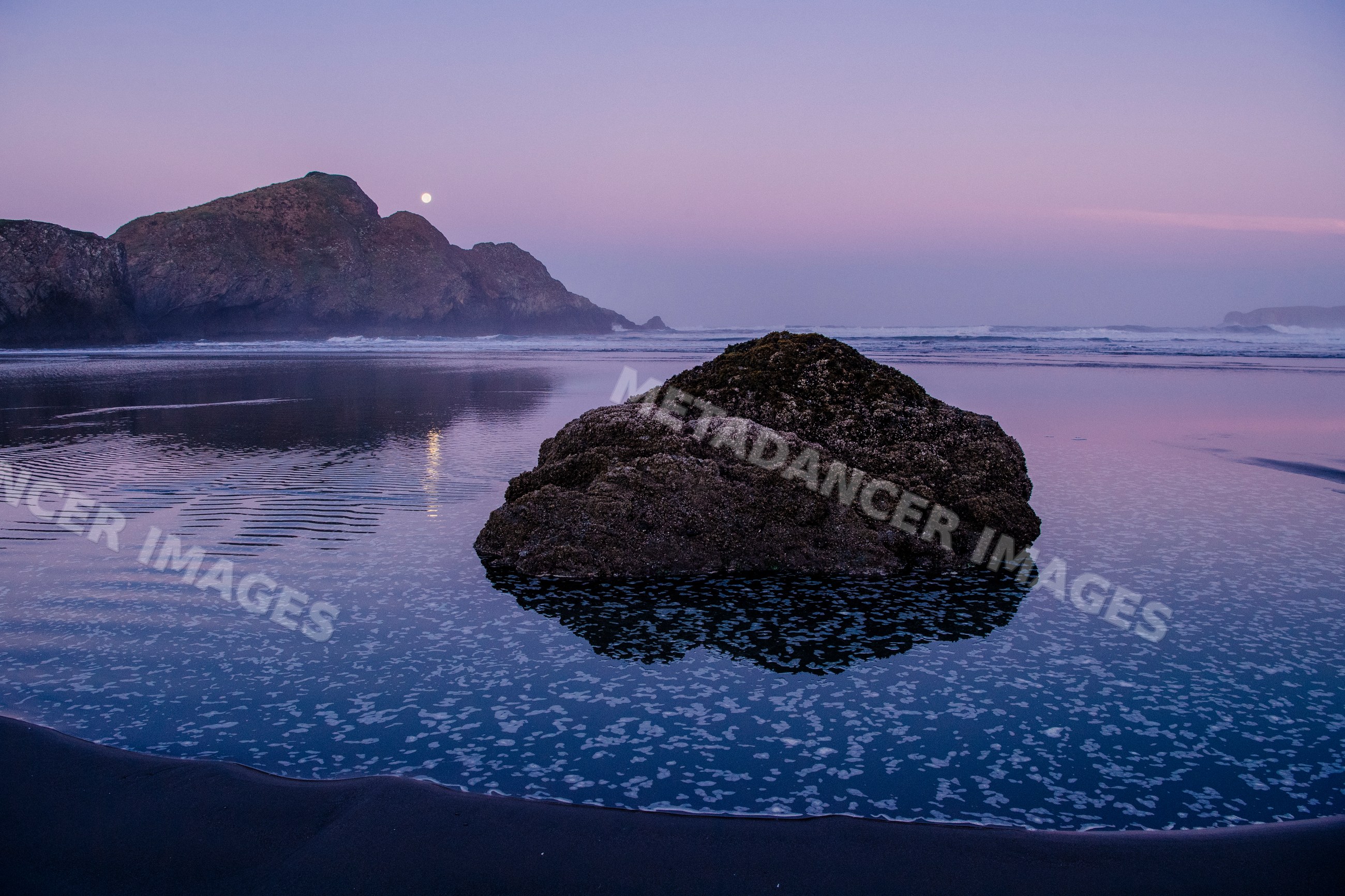 Rock formation reflecting on coastal water