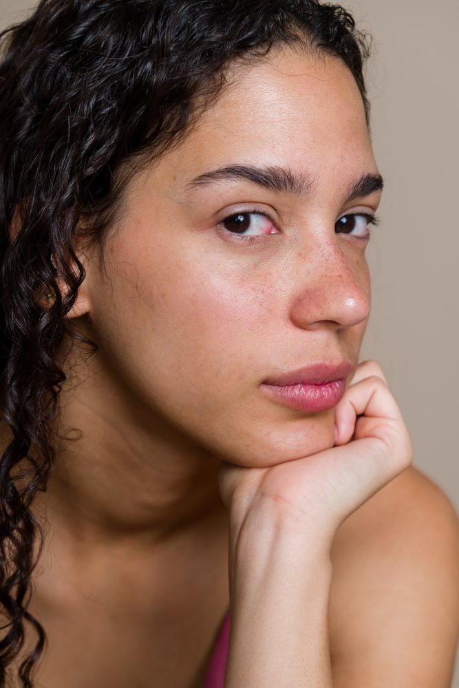 Close-up portrait of Hispanic woman with curly hair resting chin
