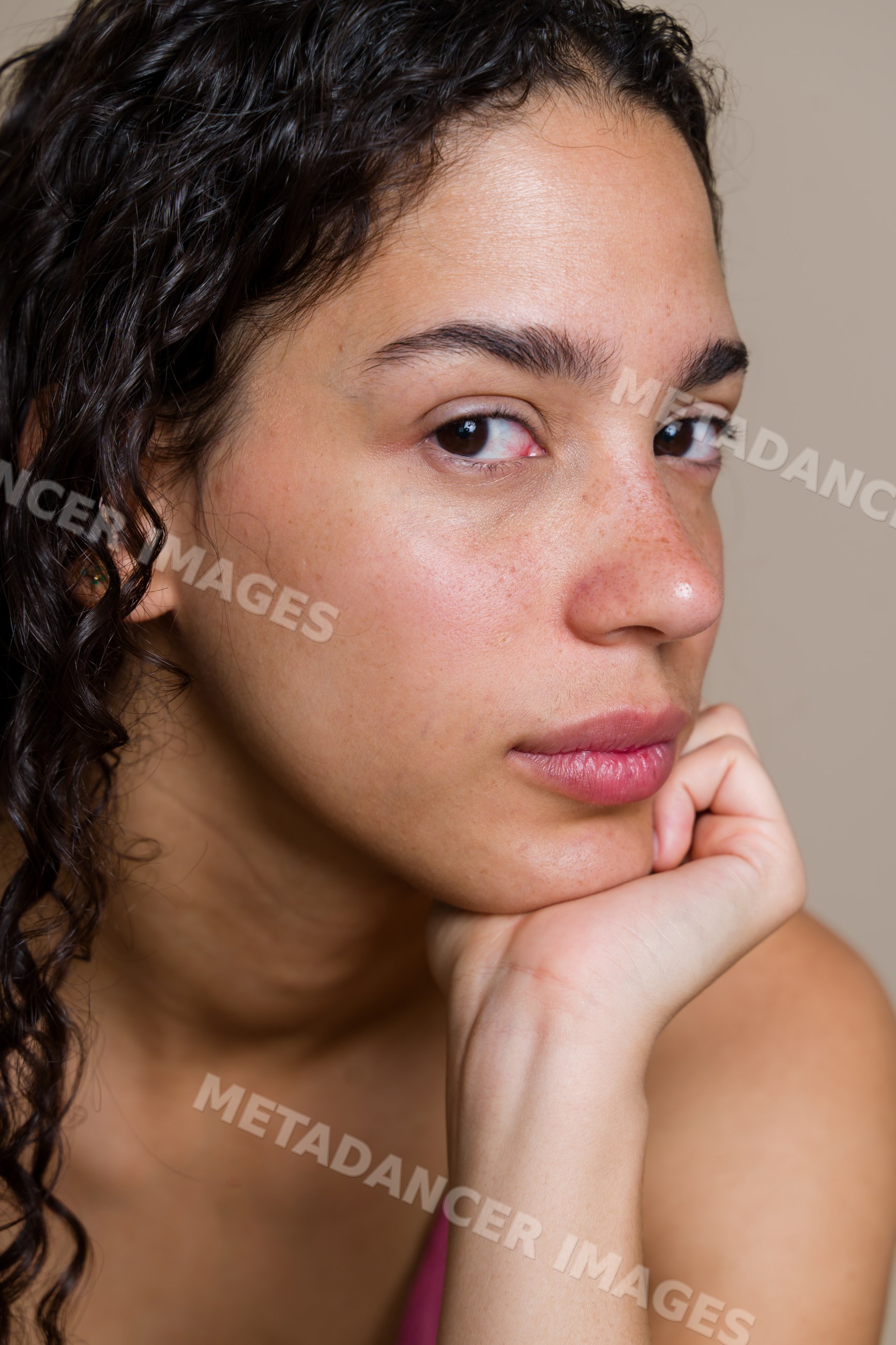 Close-up portrait of Hispanic woman with curly hair resting chin