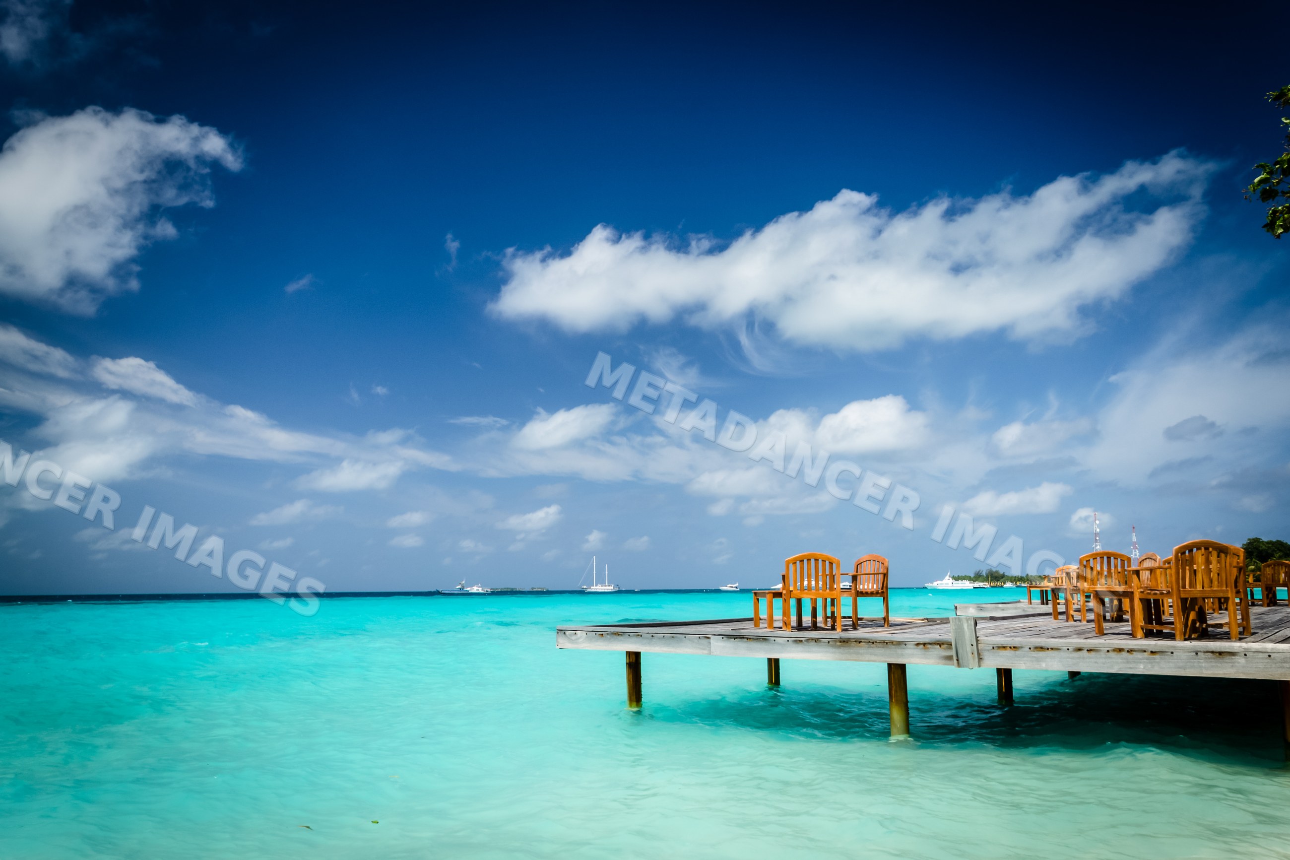 Wooden dock with chairs over turquoise water
