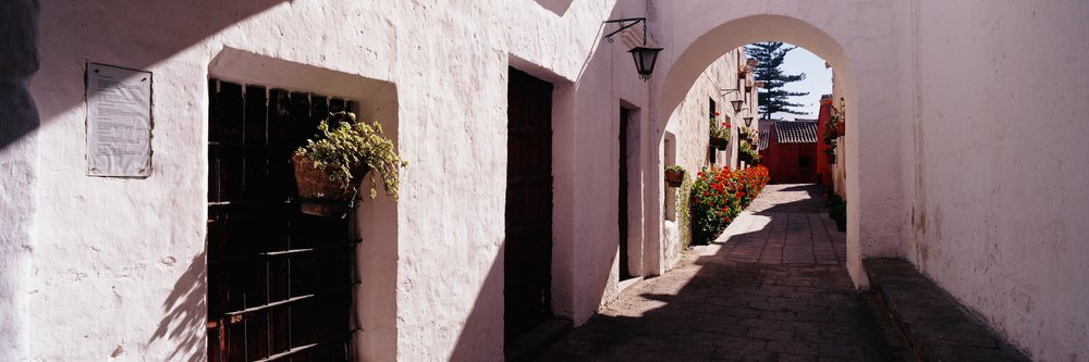 Sunlit archway with plants and pathway at santa catalina monastery