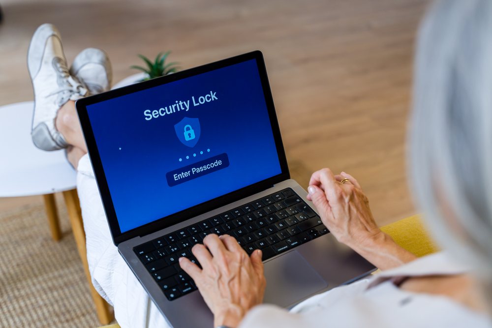 Senior white person entering passcode on laptop security lock screen