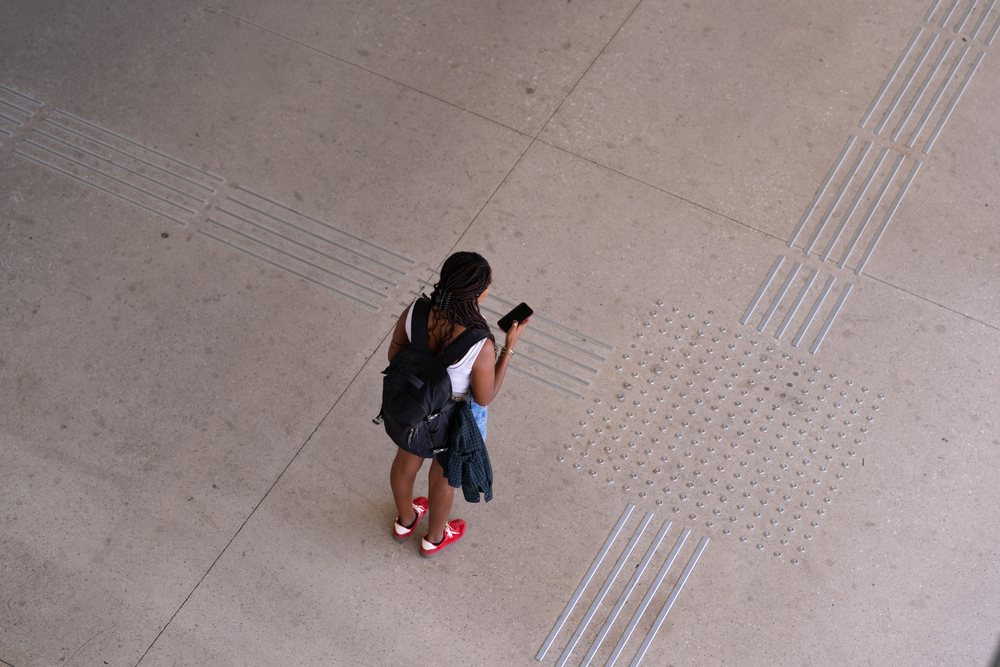 African American woman standing on tactile paving floor looking