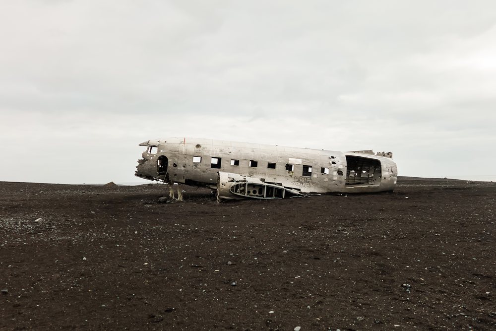An abandoned crashed airplane fuselage on a black sand desert