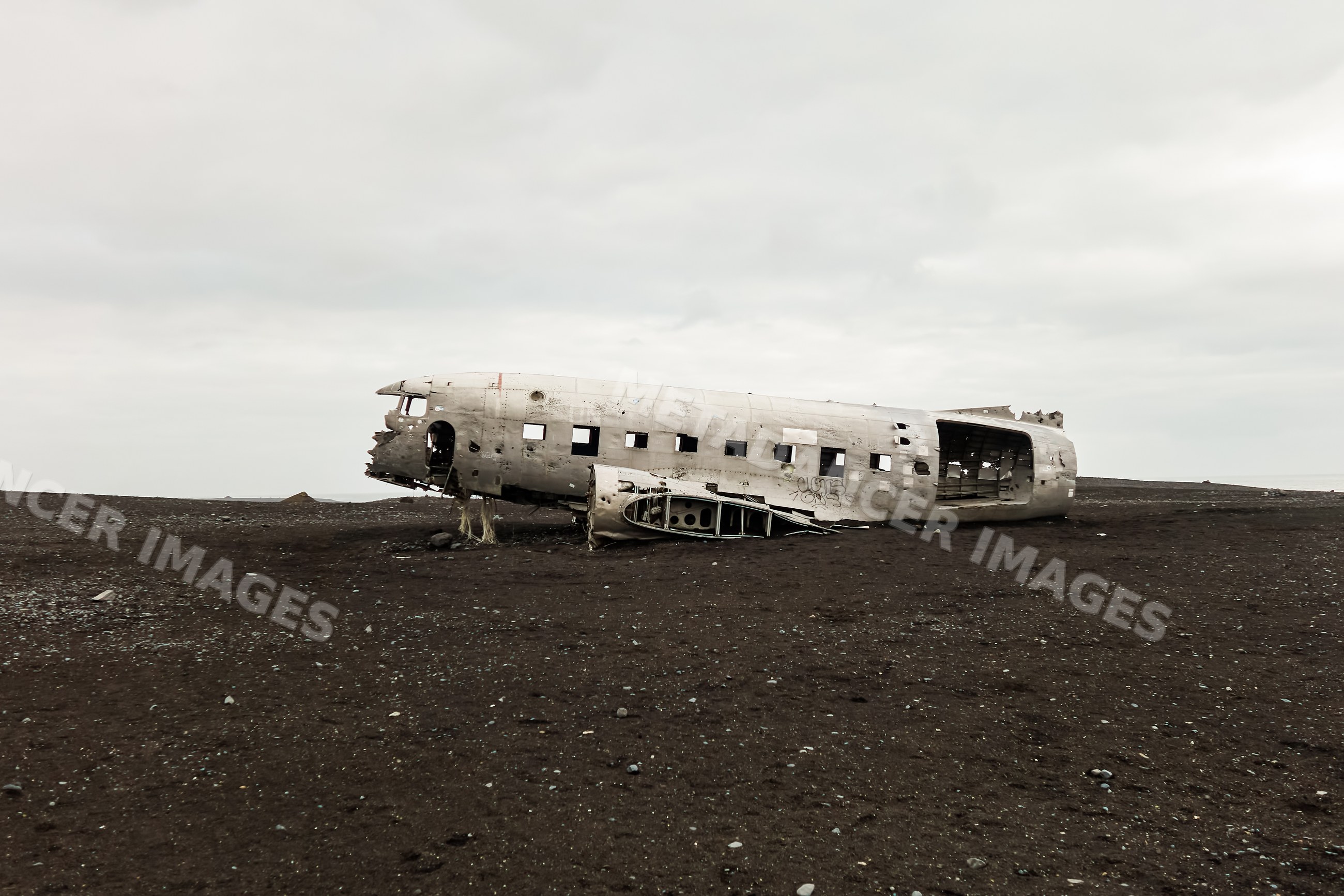 An abandoned crashed airplane fuselage on a black sand desert