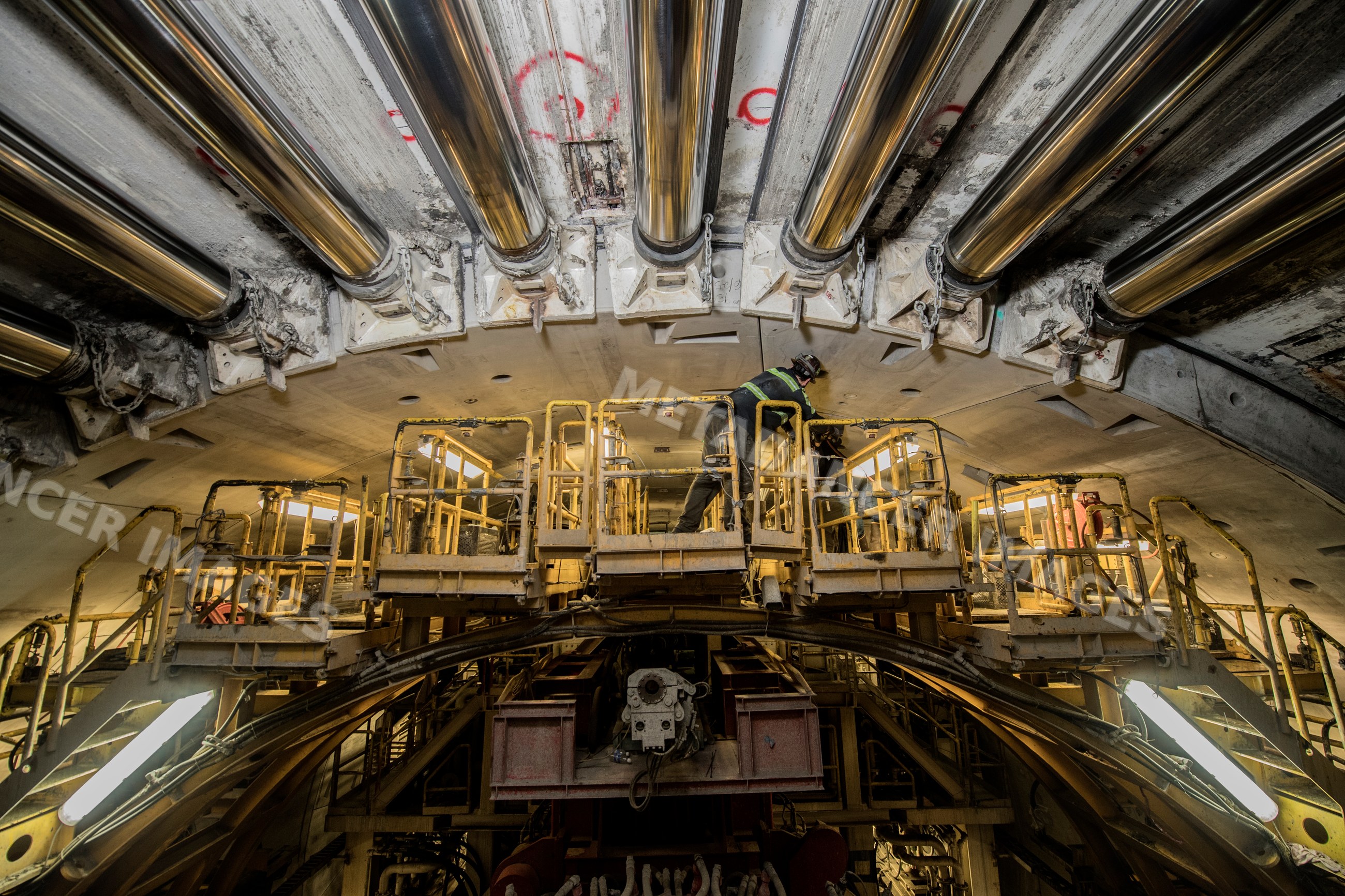 A construction worker inspects a drilling machine inside a tunnel