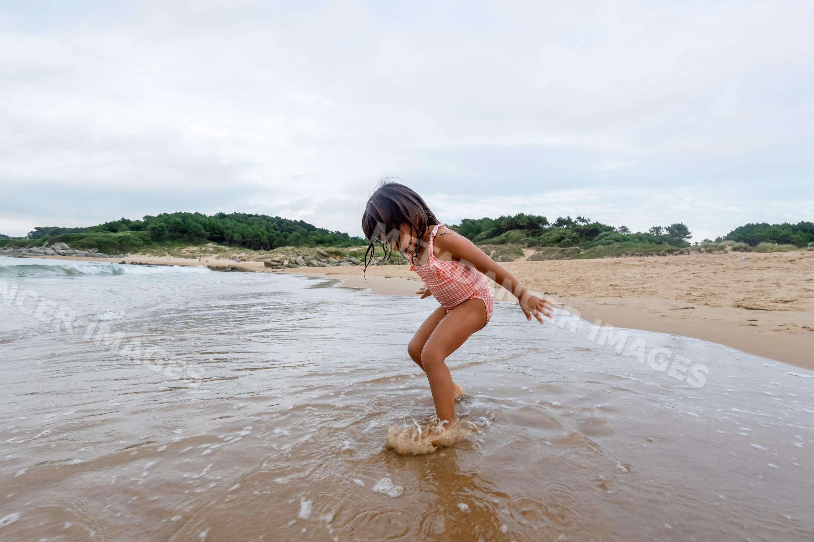 White child splashing water at sandy beach shoreline in a beach