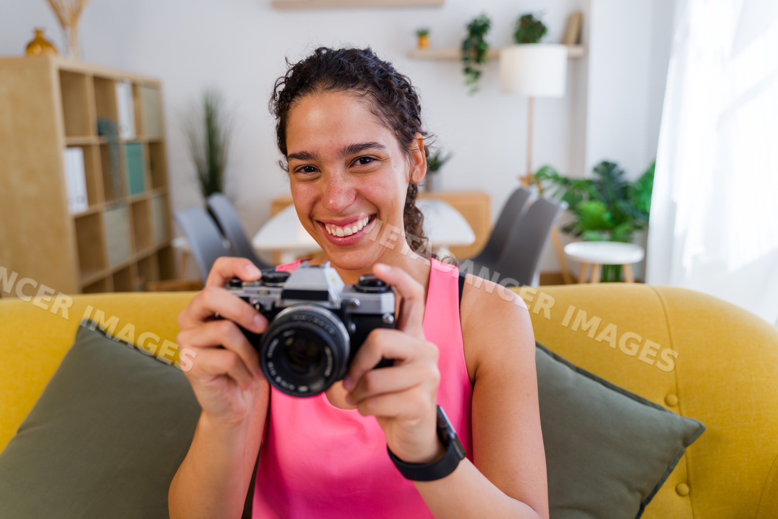 A young Hispanic woman happily holds a camera