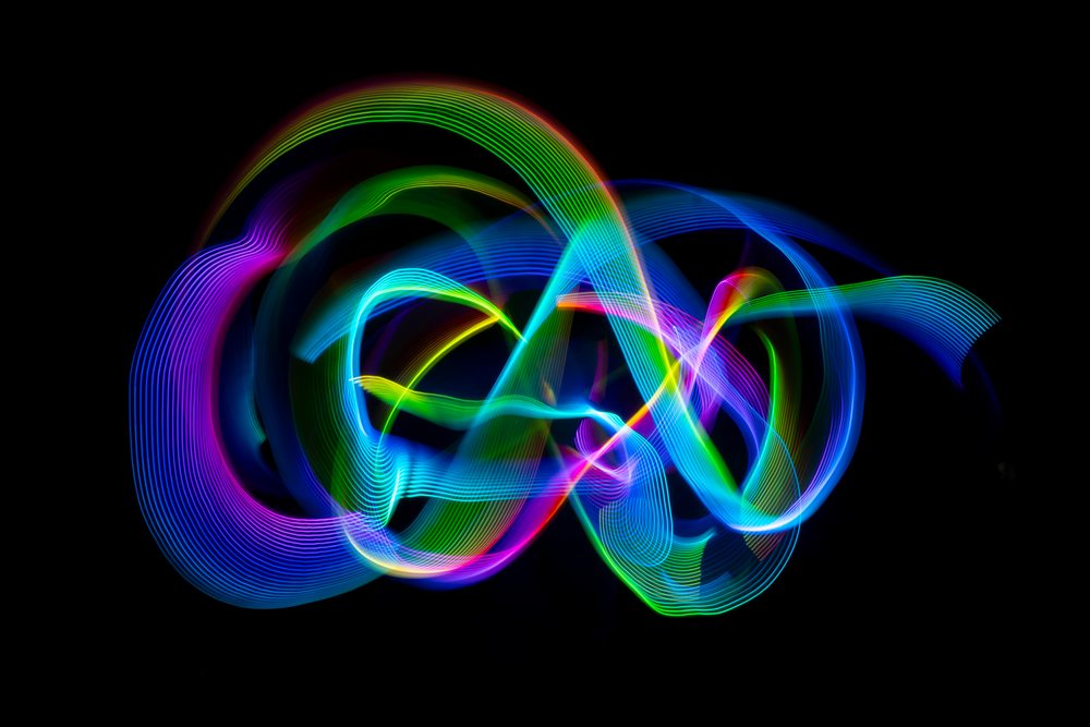 Colorful light painting creating swirling trails on dark background