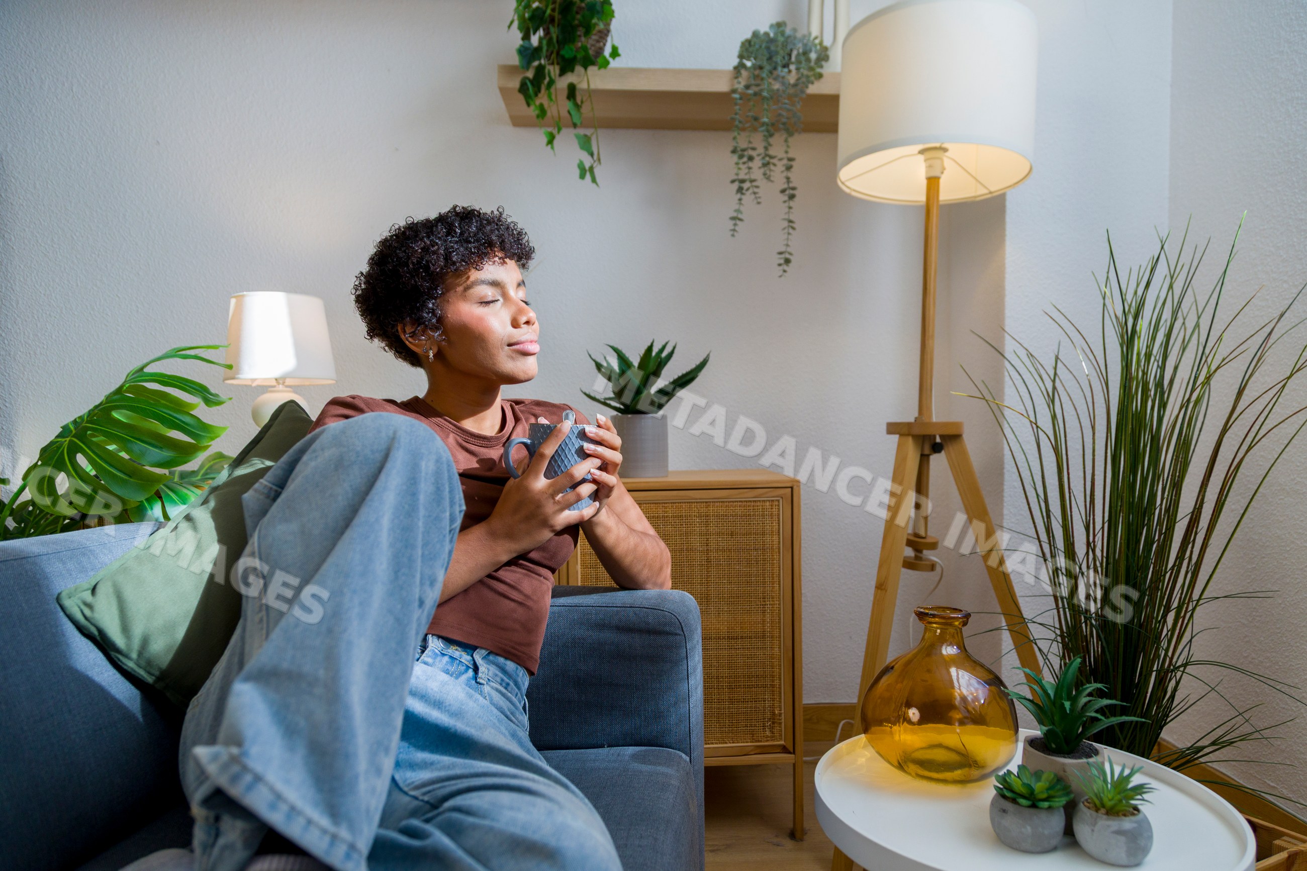 African American woman relaxing on sofa holding coffee cup at home