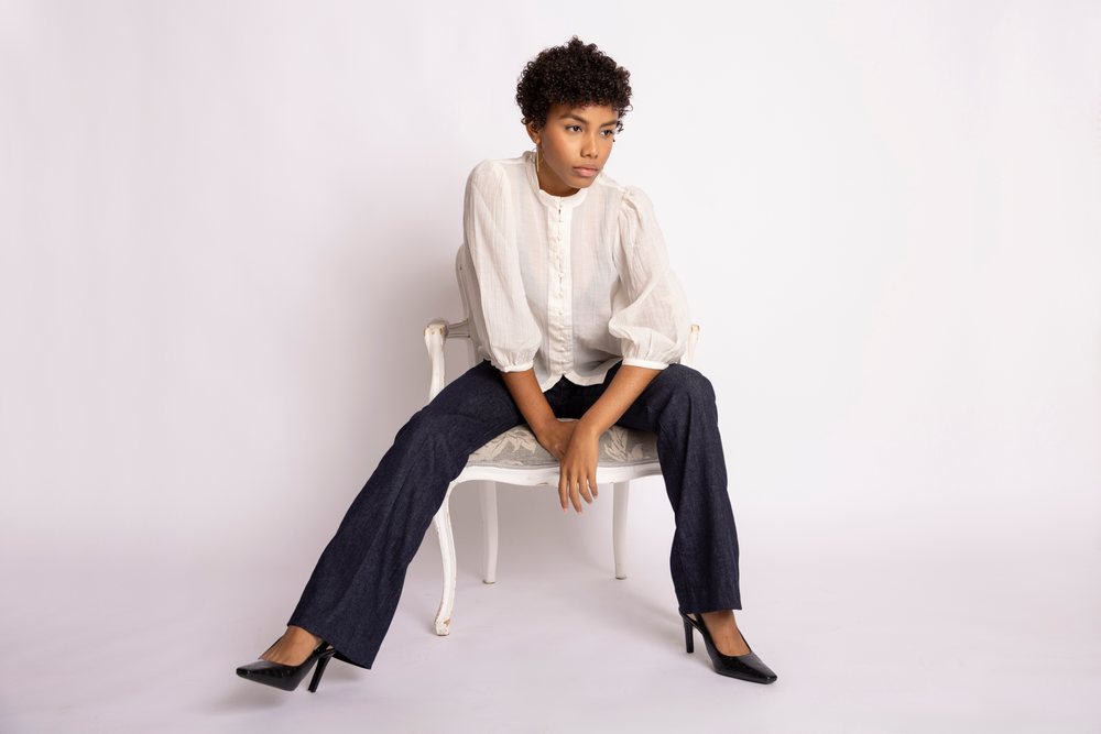 Hispanic woman sitting on a chair wearing white blouse and dark pants