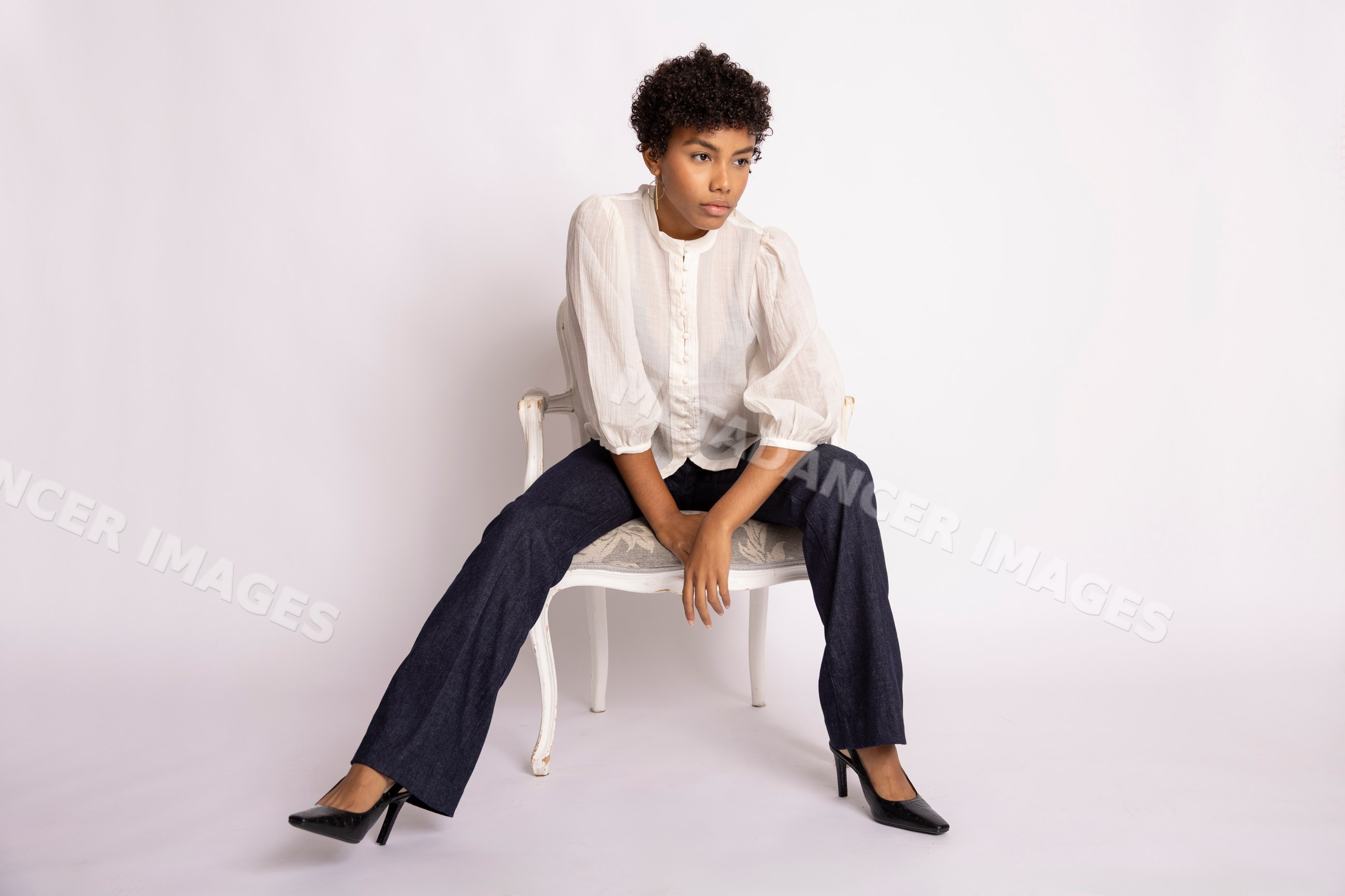 Hispanic woman sitting on a chair wearing white blouse and dark pants