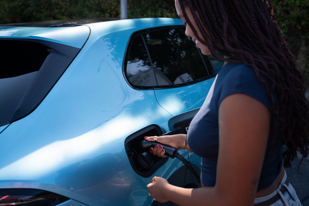 A African American woman charges an electric car outdoors in Spain