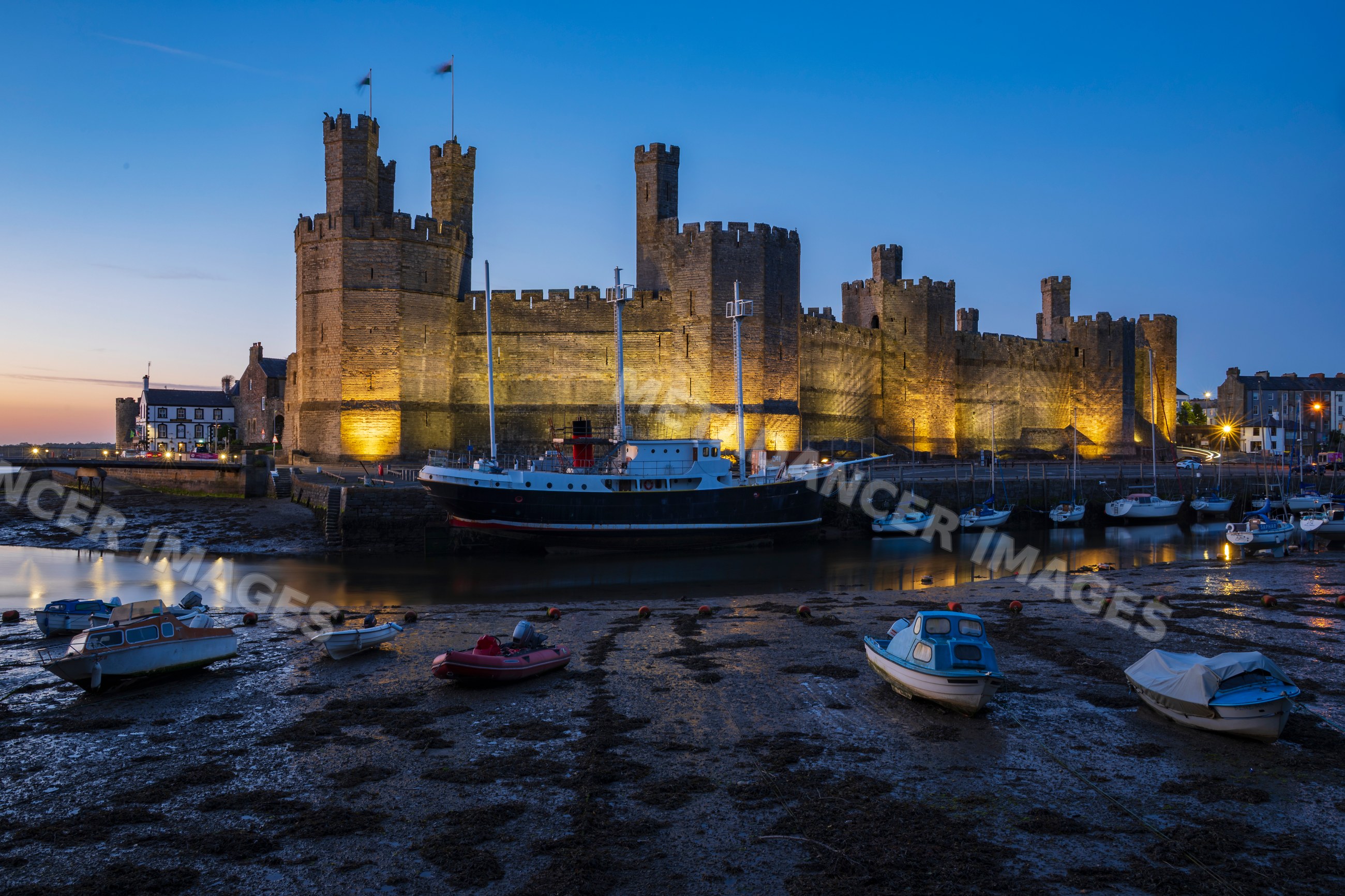 Caernarfon castle walls and harbour at Low Tide at Dusk in Wales