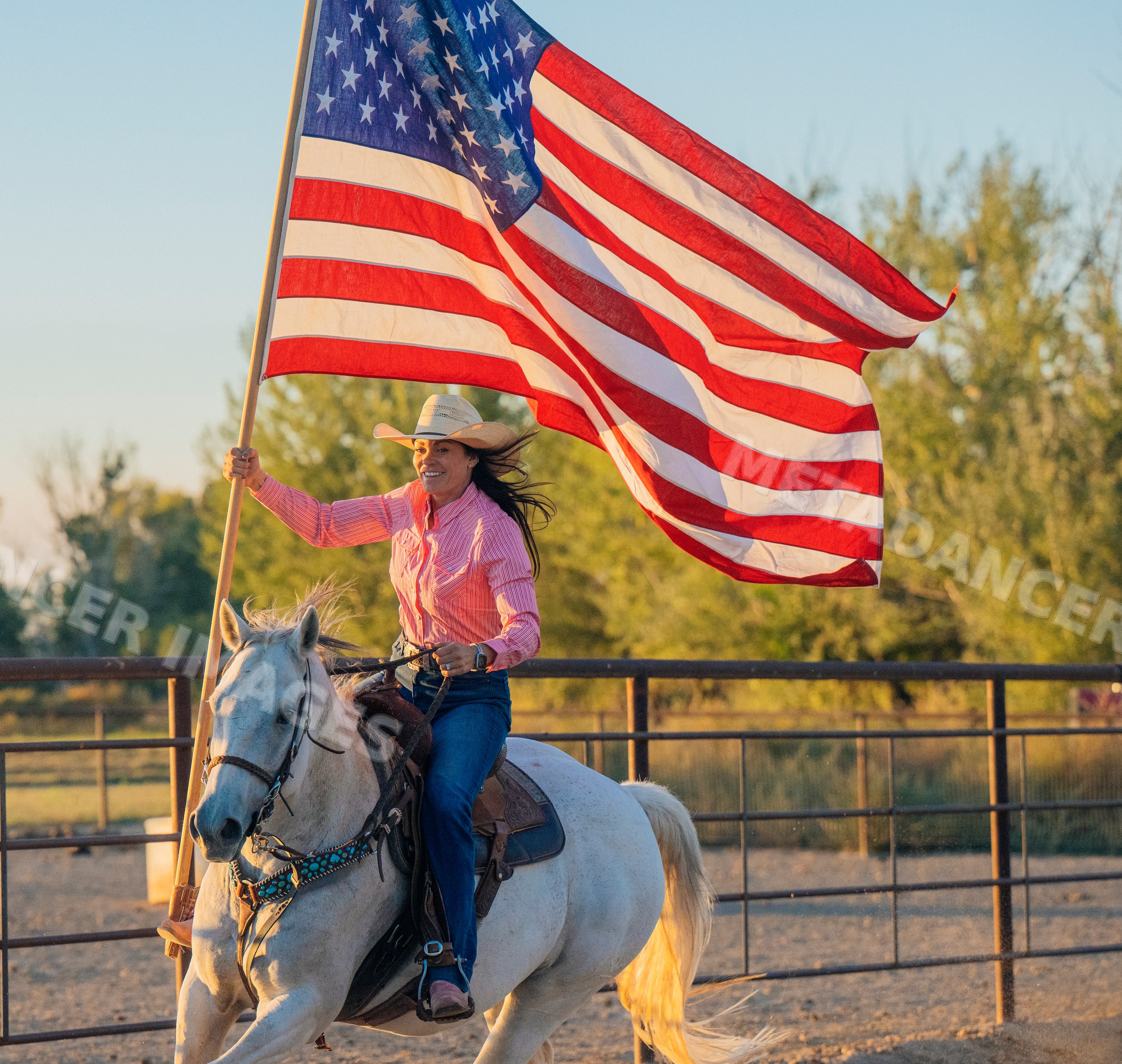 White woman riding horse carrying american flag
