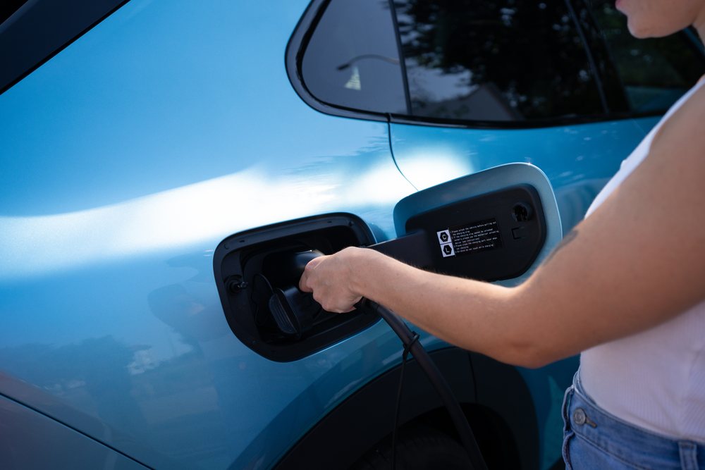 A white person charges an electric car with a cable
