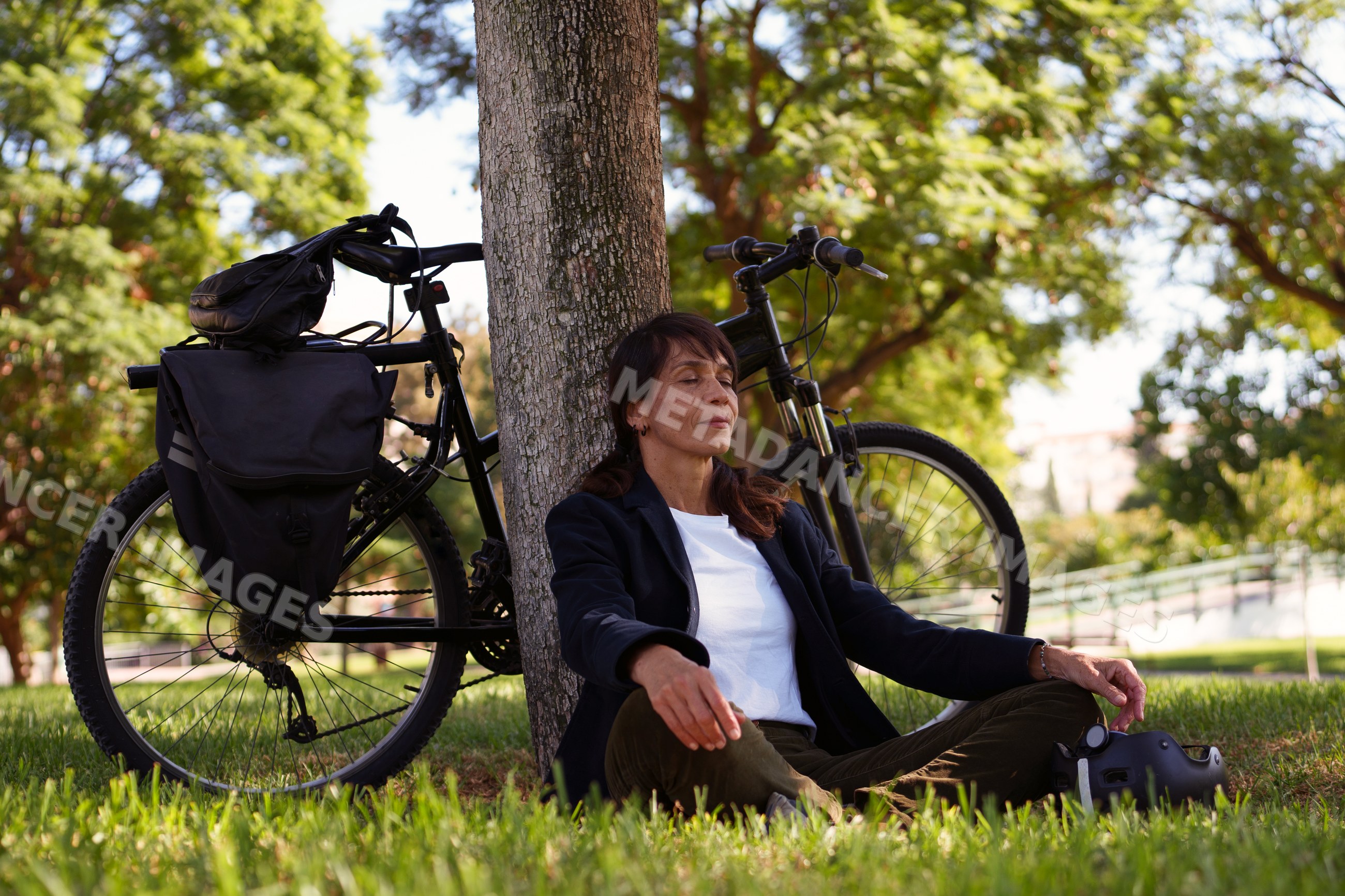Hispanic woman meditating by tree
