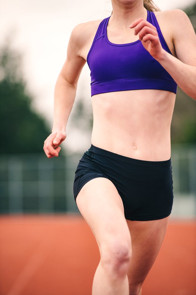 White female runner sprinting on outdoor track