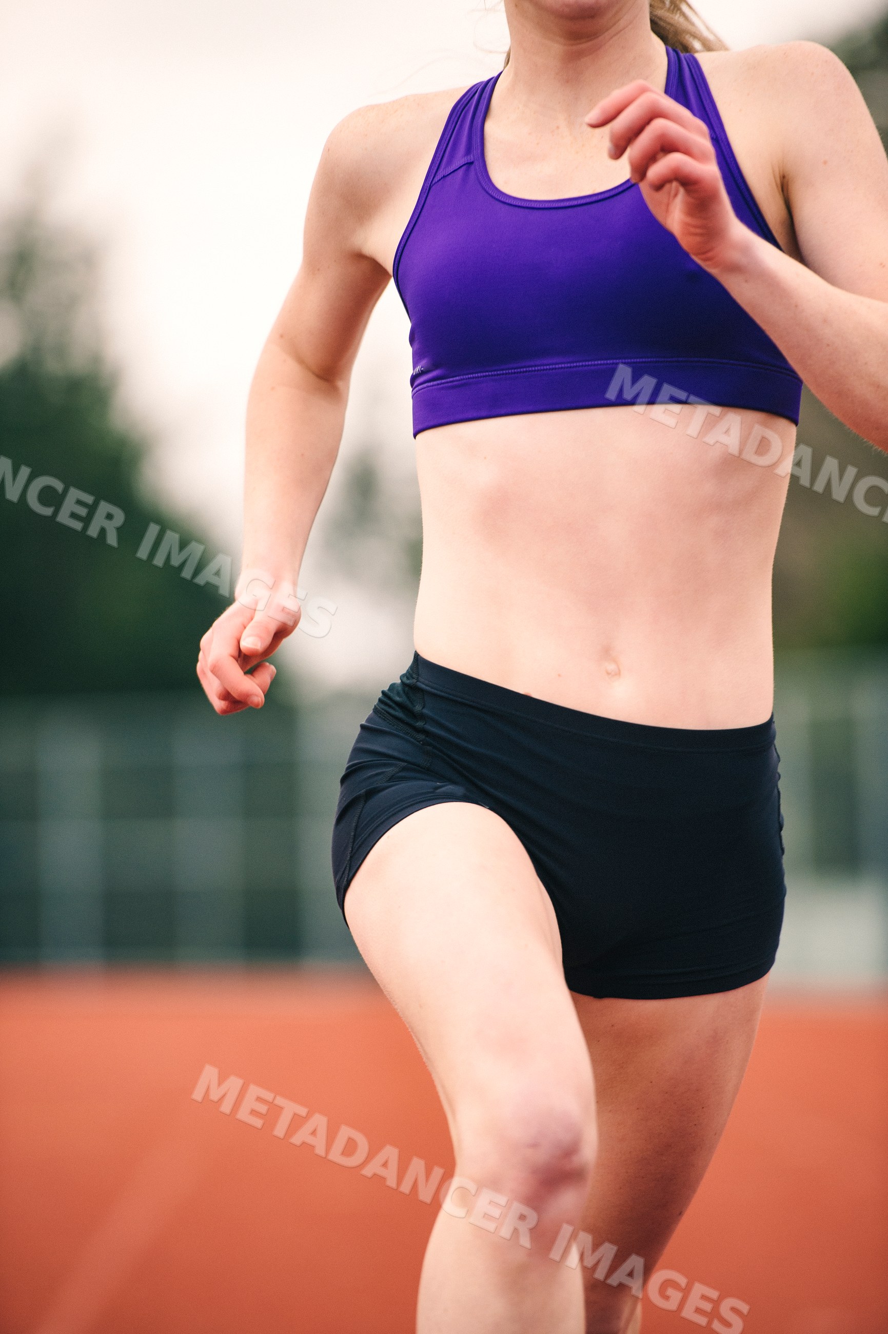 White female runner sprinting on outdoor track