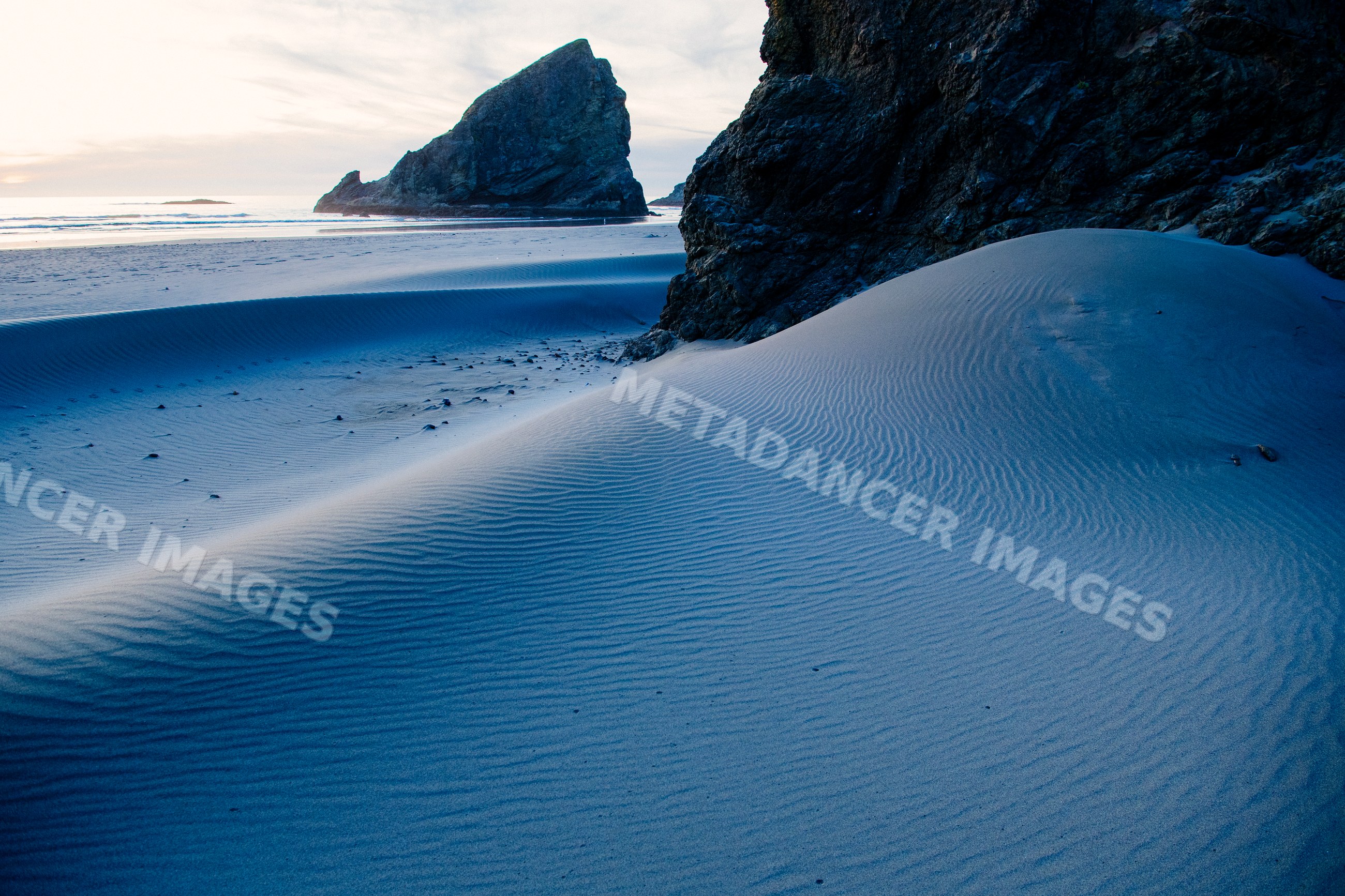 Sand dunes and rock formations on meyers creek beach at sunset
