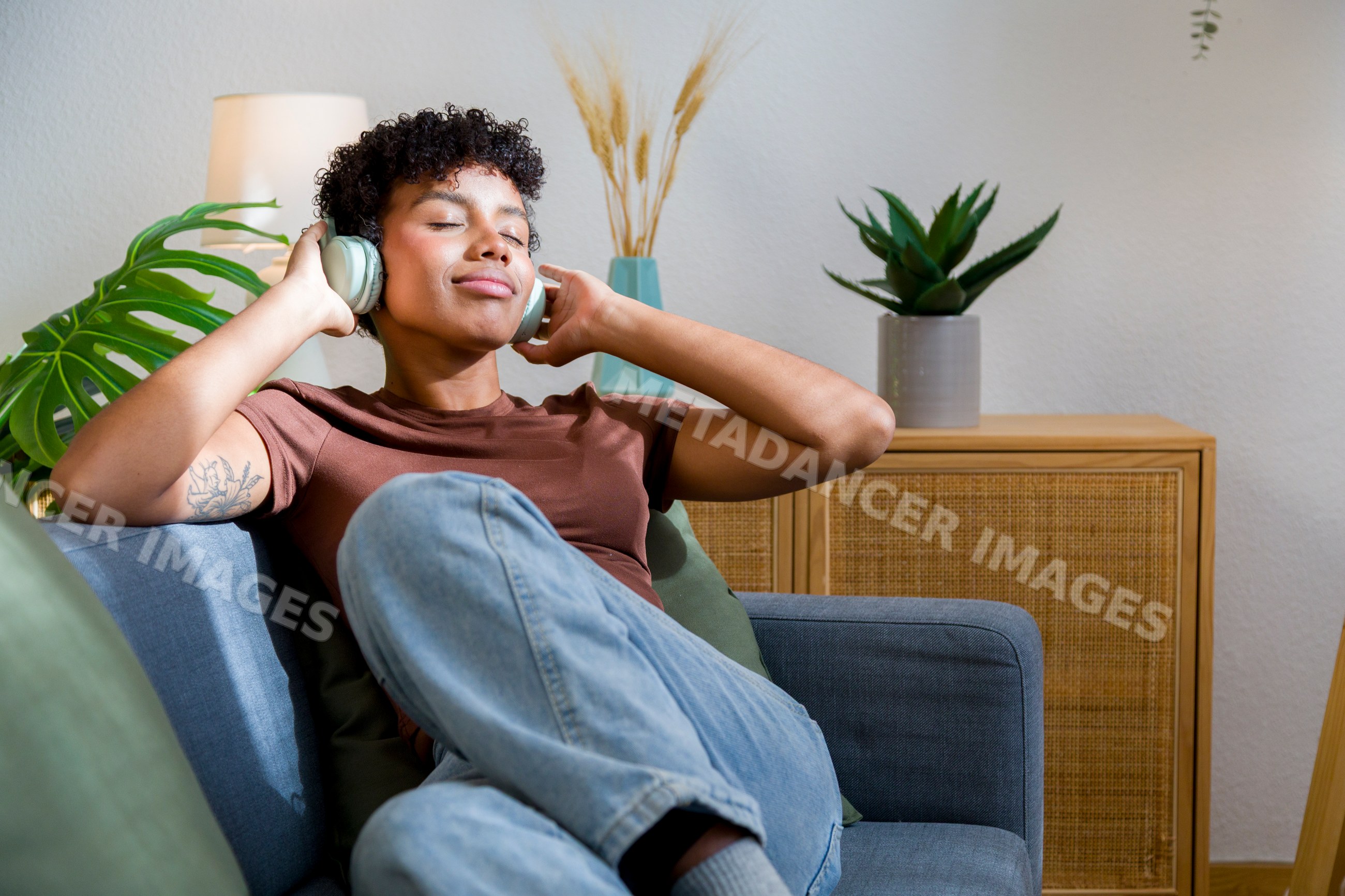 Young African American woman relaxing on sofa listening to music