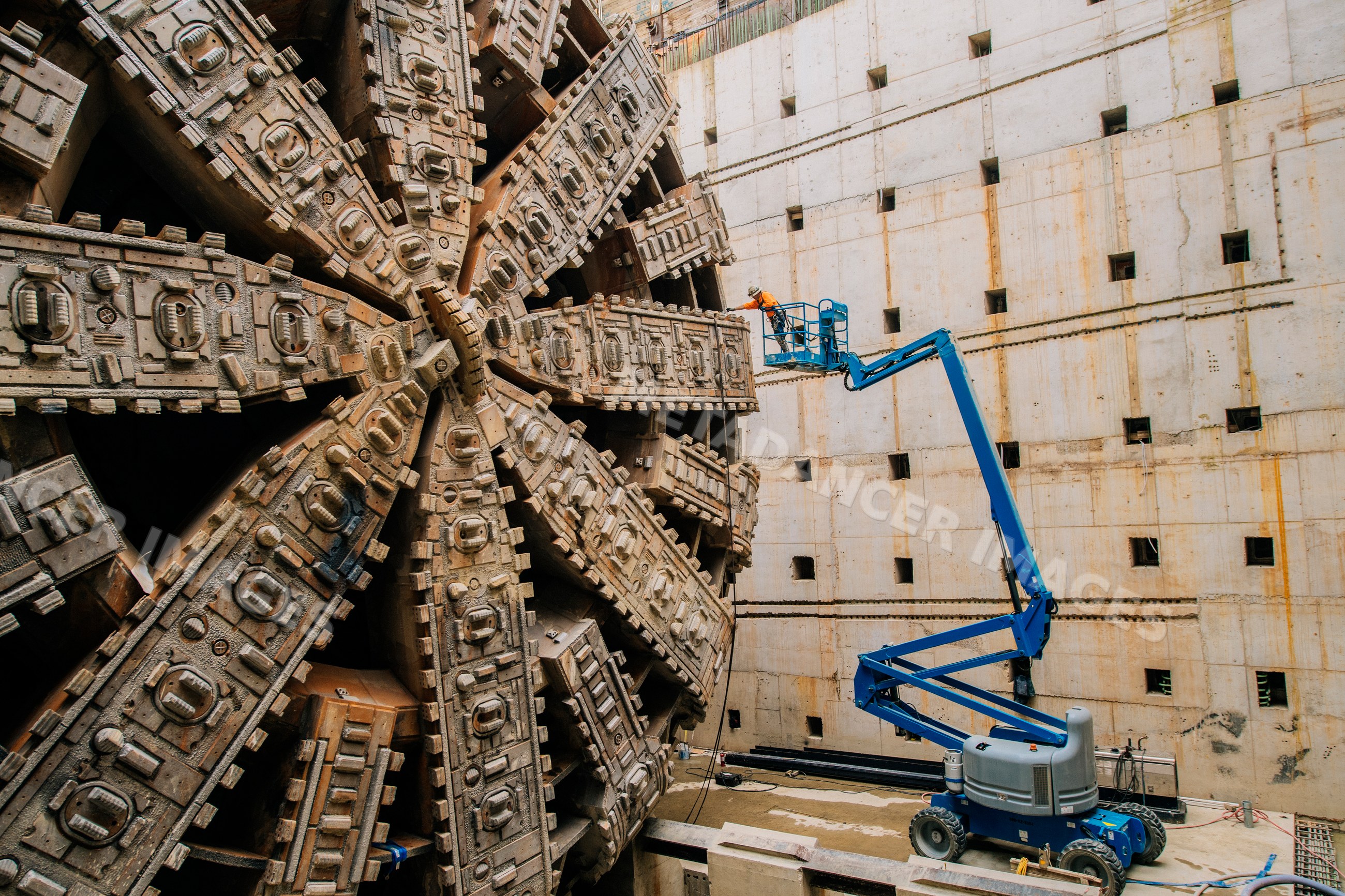 Worker inspects massive tunnel boring machine at construction site