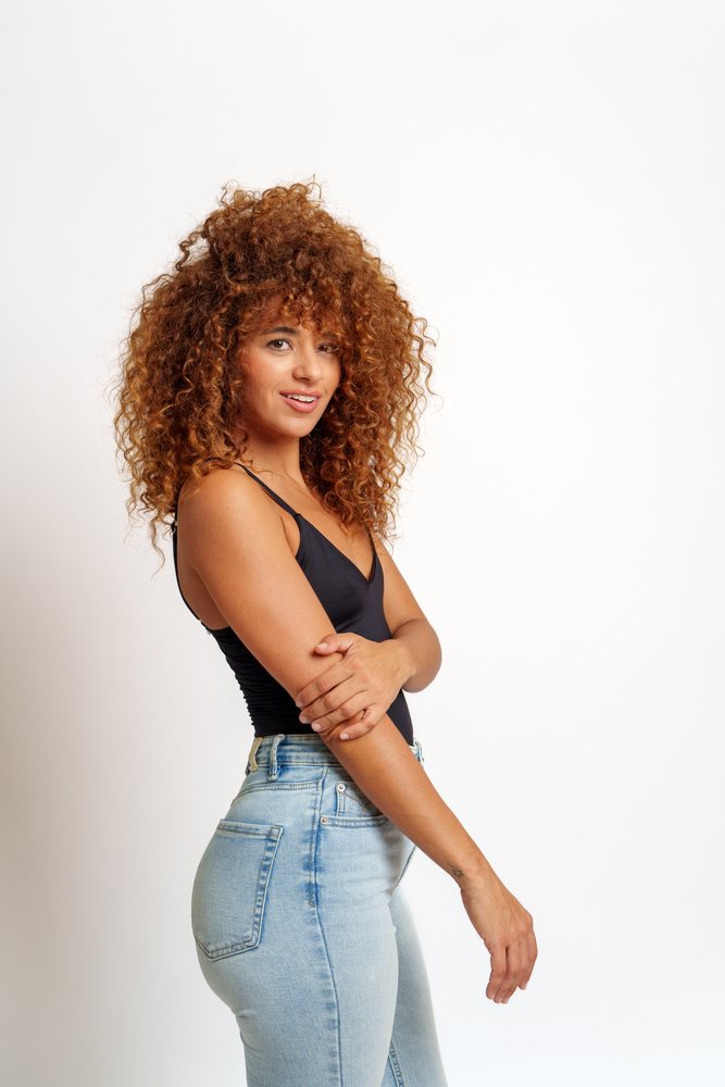 Hispanic woman with curly red hair wearing black tank top