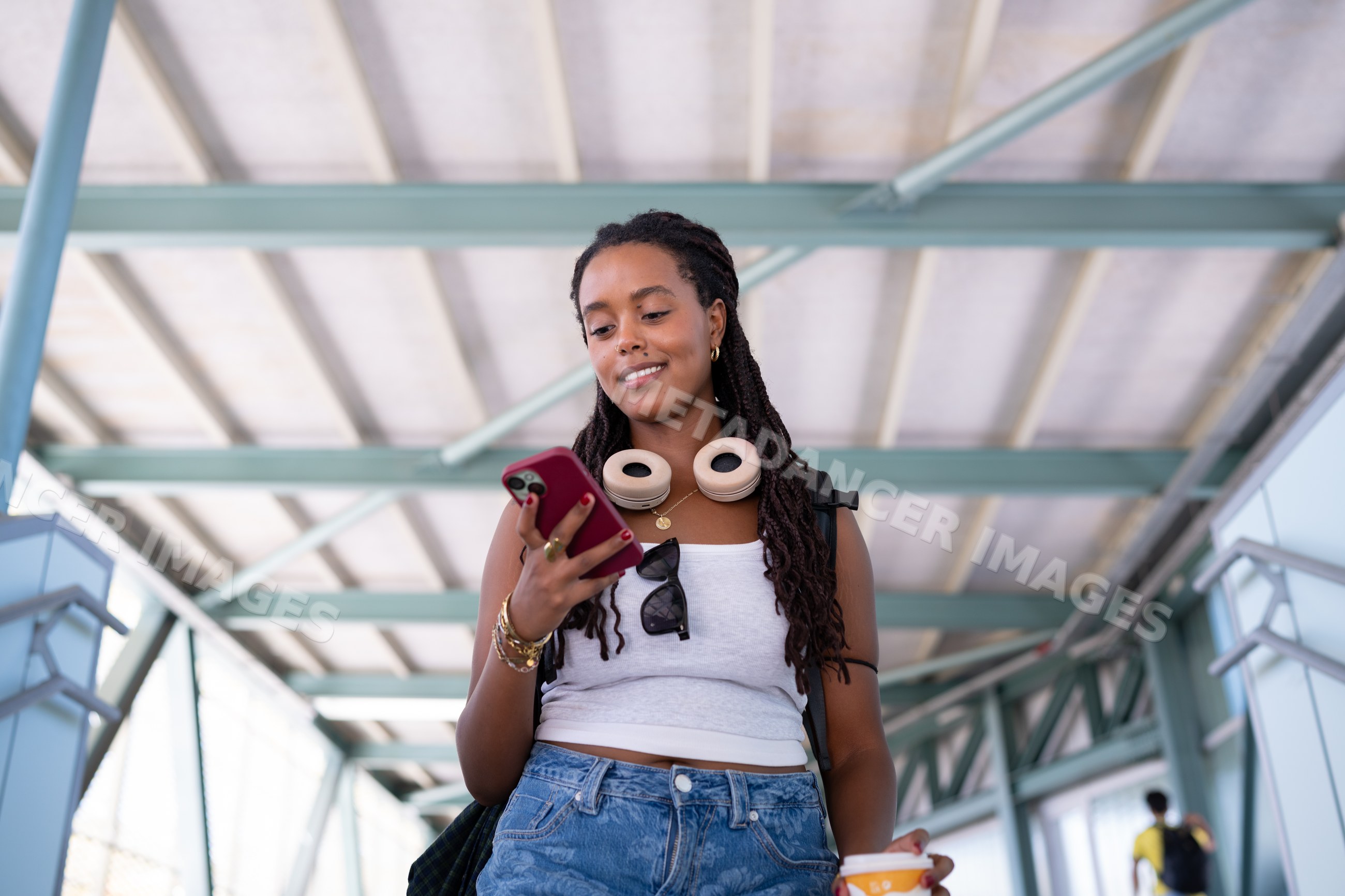 A young African American woman using her smartphone while walking