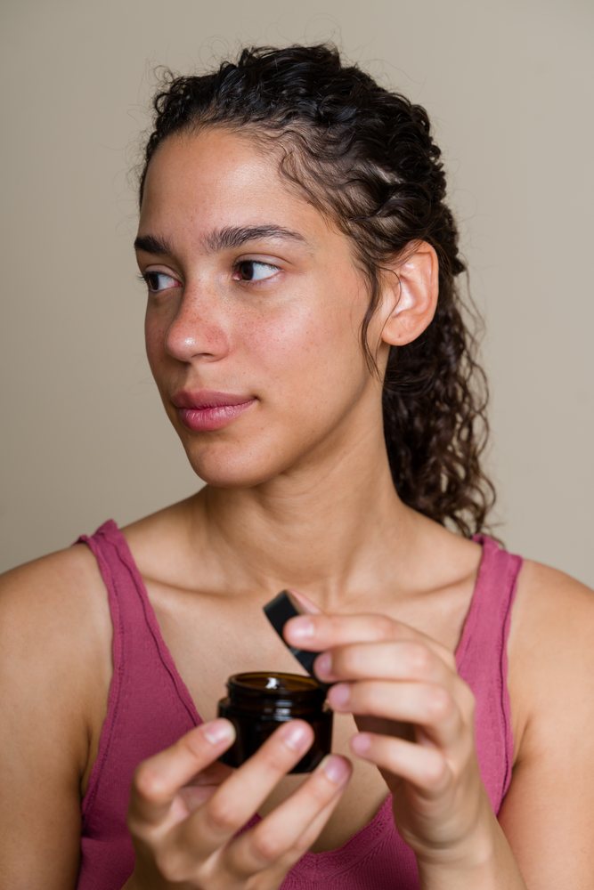 Hispanic woman holding skin care cream jar in a beauty shoot