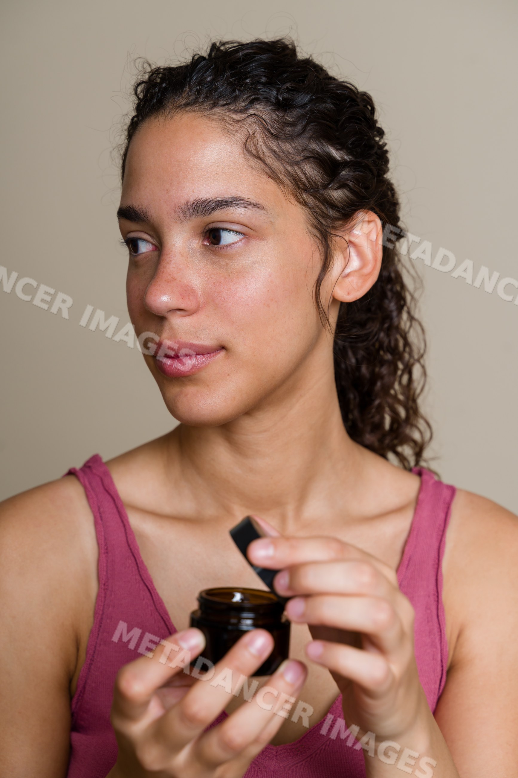 Hispanic woman holding skin care cream jar in a beauty shoot
