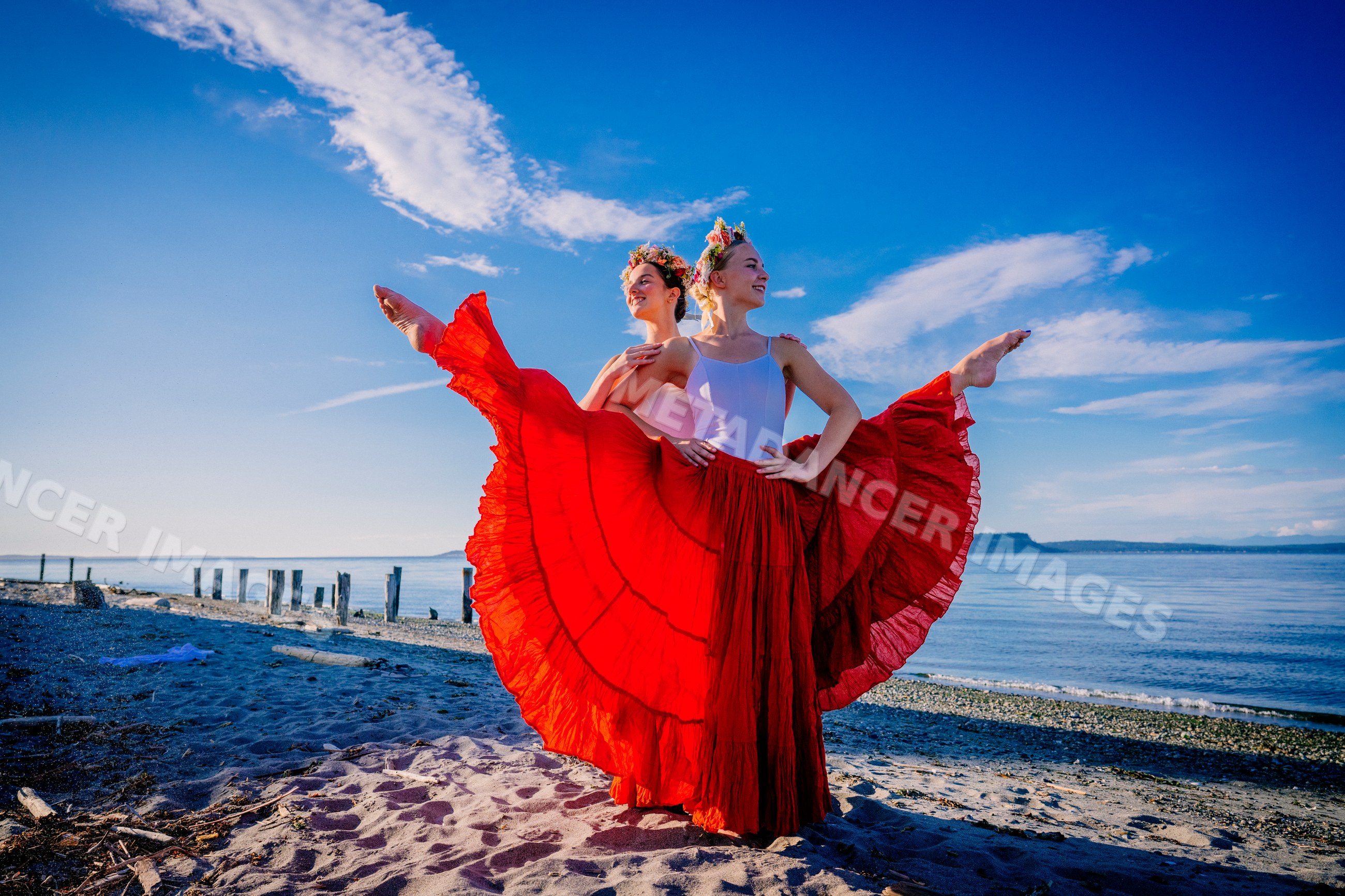 Two white women doing partner acrobatics yoga on a beach in WA, USA