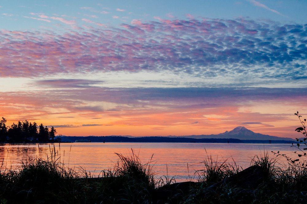 Sunset over water with mount rainier and ferry