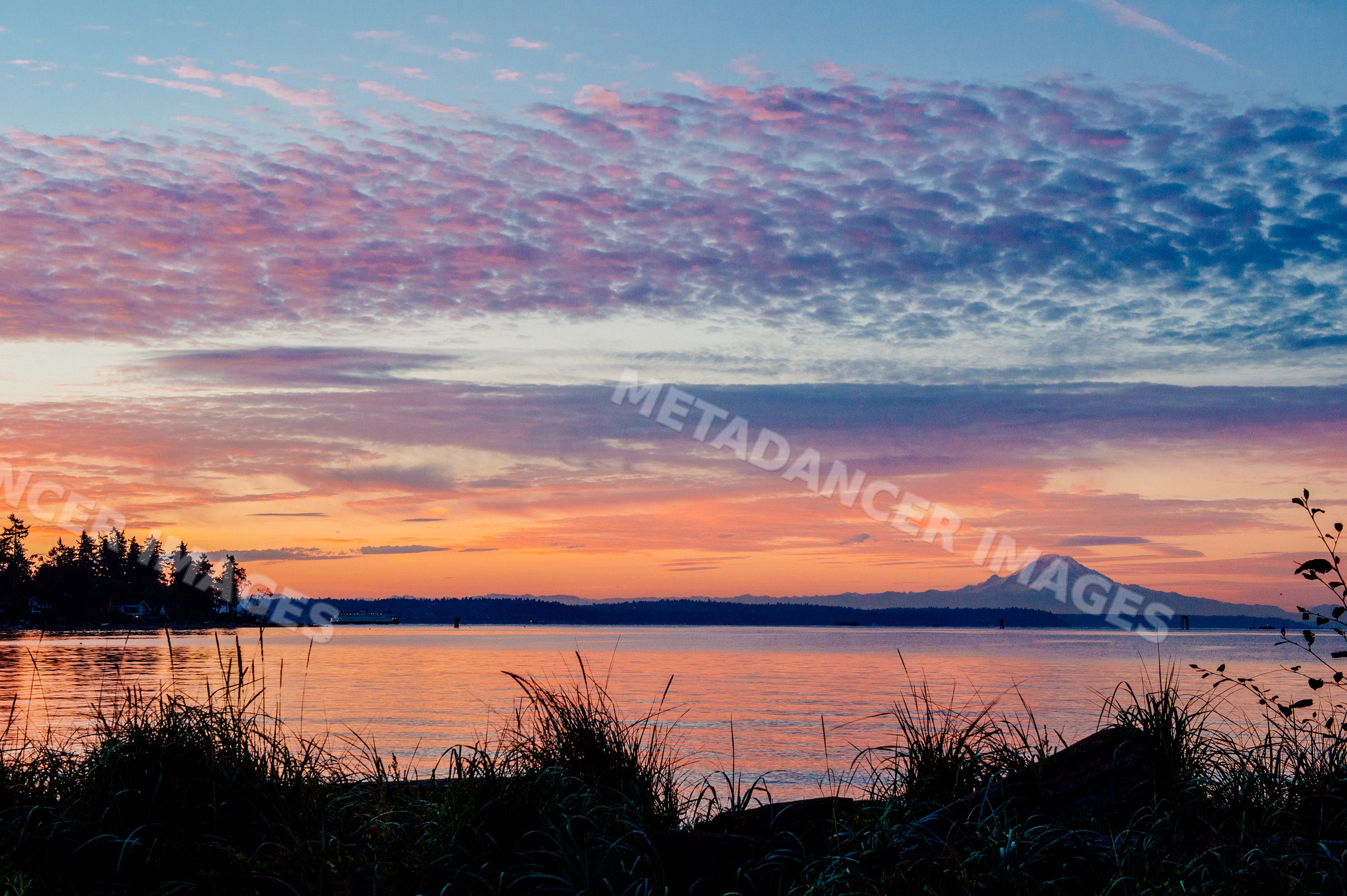 Sunset over water with mount rainier and ferry