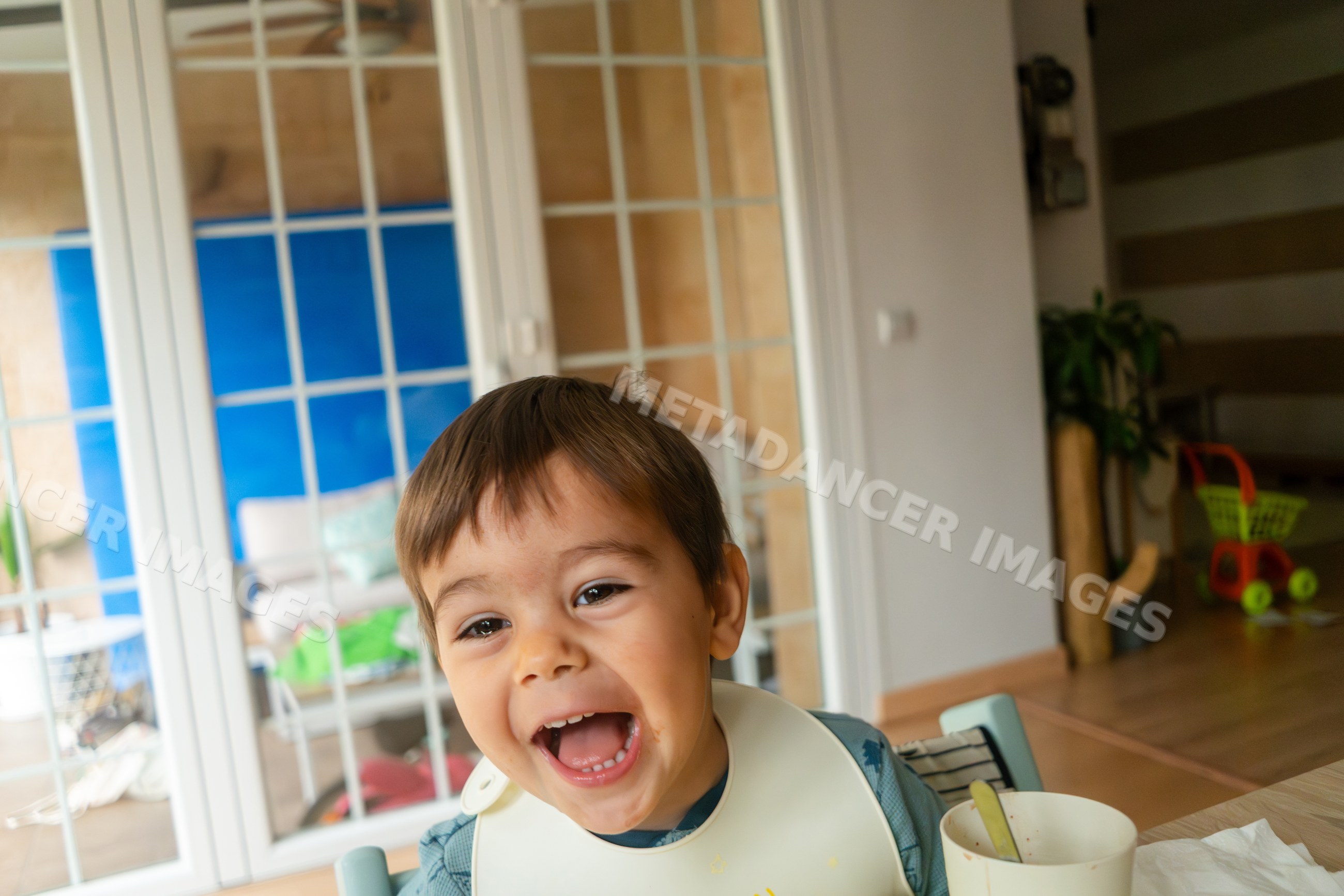 Happy toddler white boy laughing during mealtime