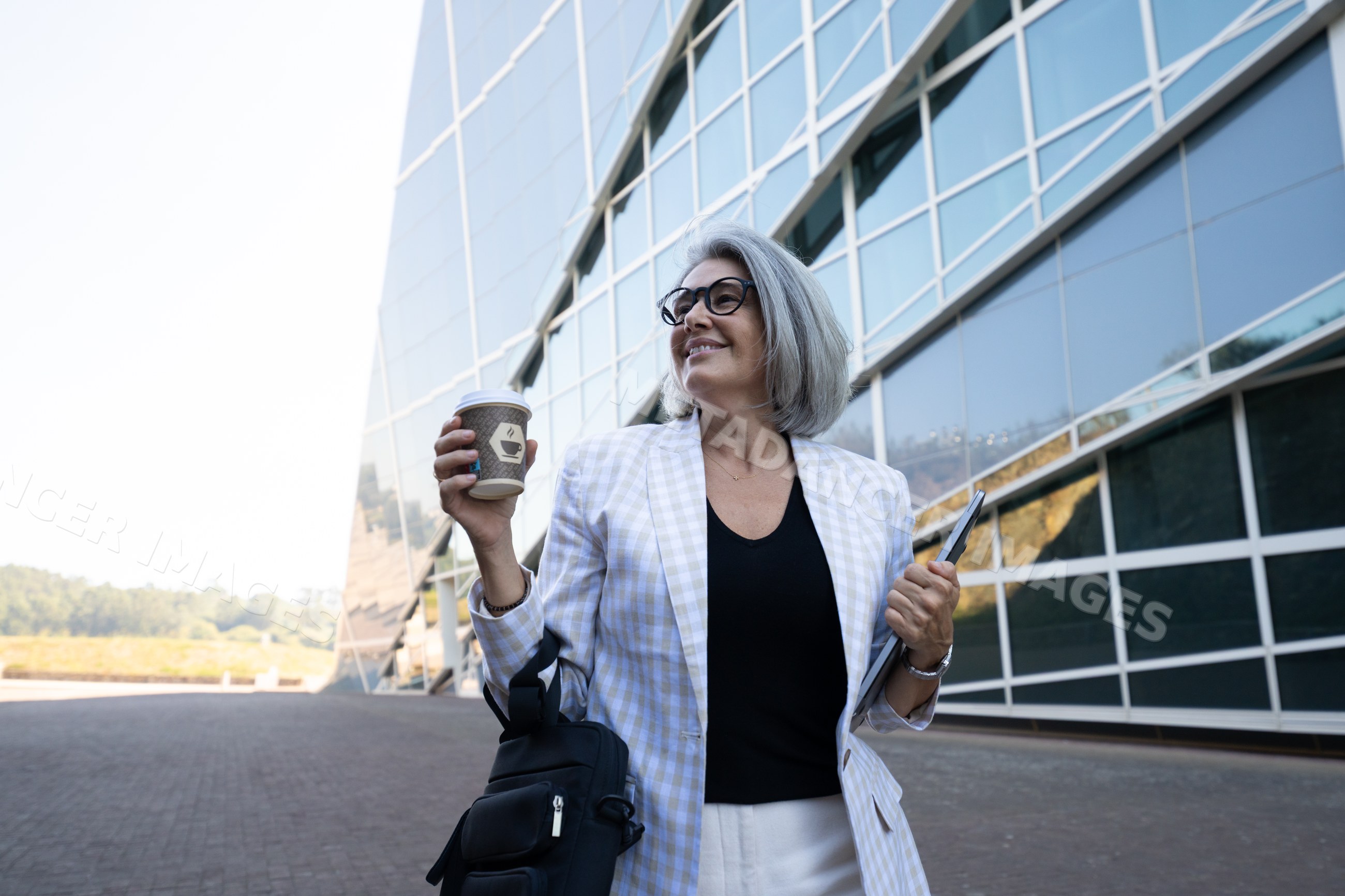 Businesswoman with coffee and tablet outside modern office in a office