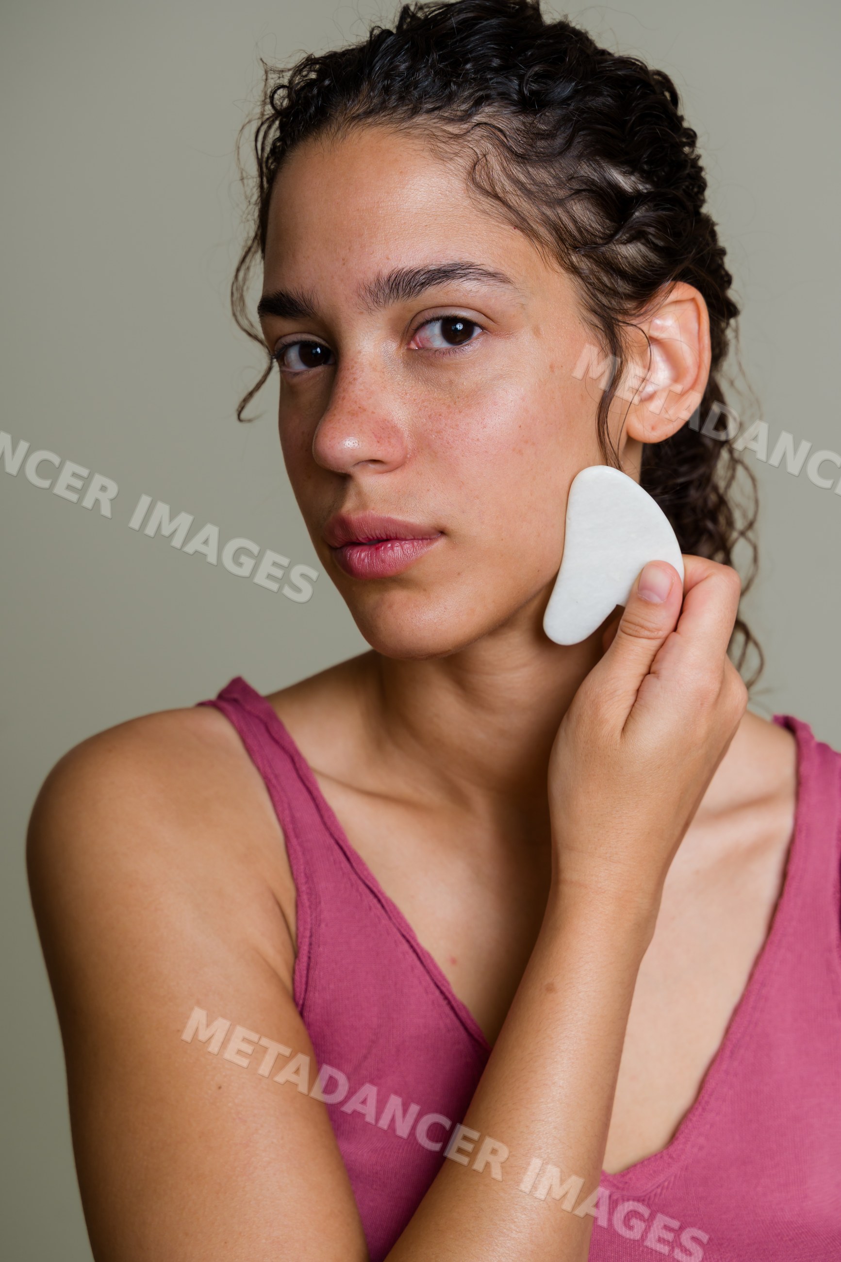 Hispanic woman performing facial massage with gua sha tool