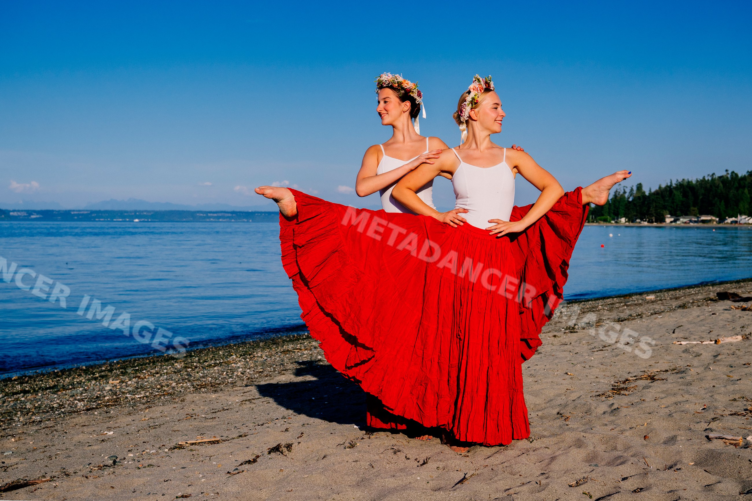 Two white women performing partner acrobatics on a beach in wa USA