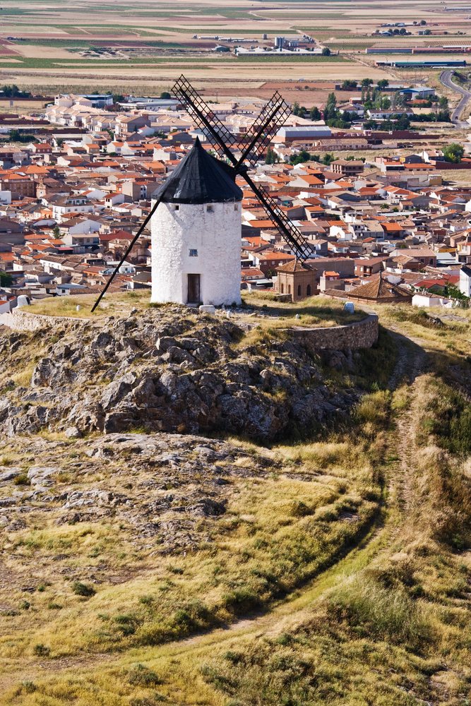 Windmill on rocky hill overlooking village and fields, Spain