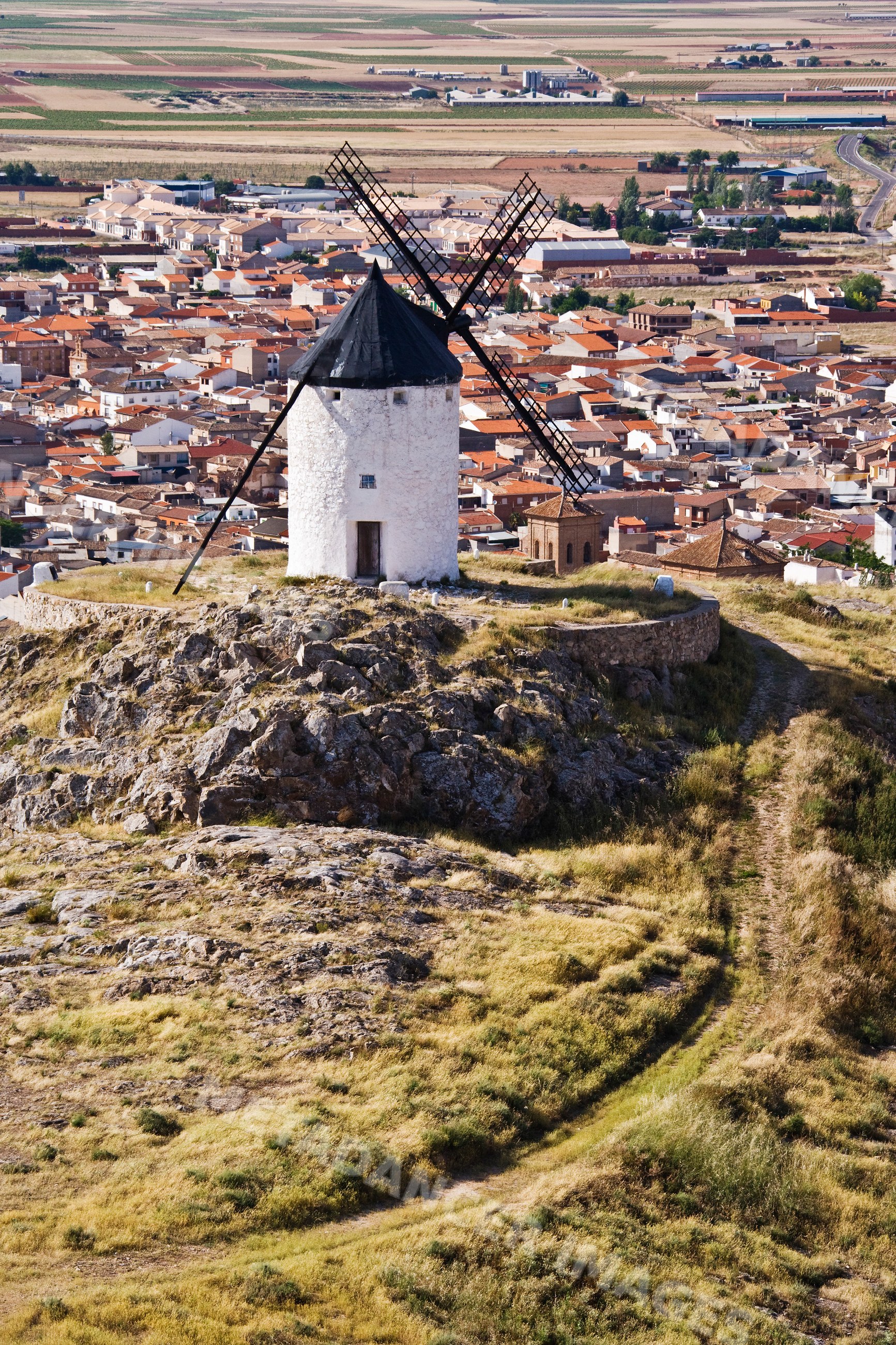 Windmill on rocky hill overlooking village and fields, Spain