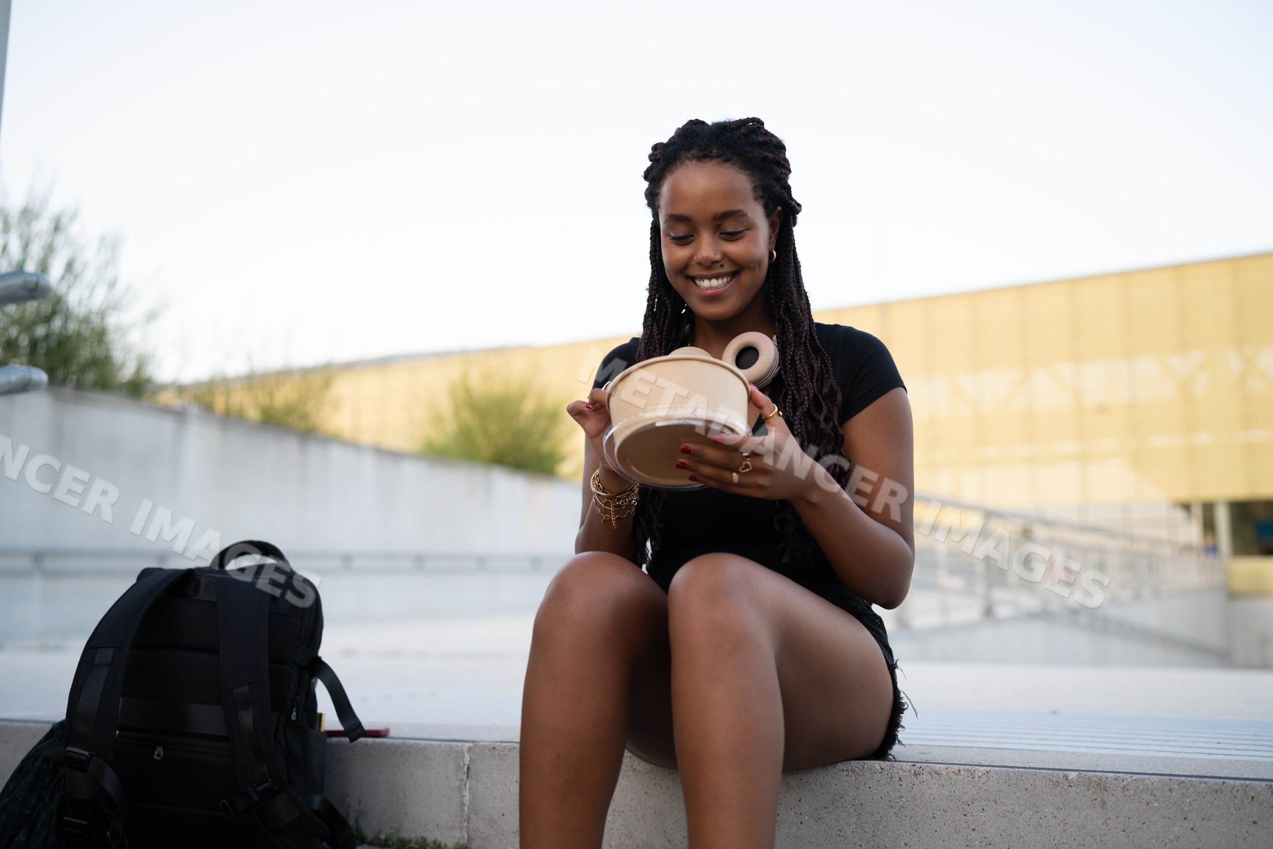 A young African American woman happily eating outdoors