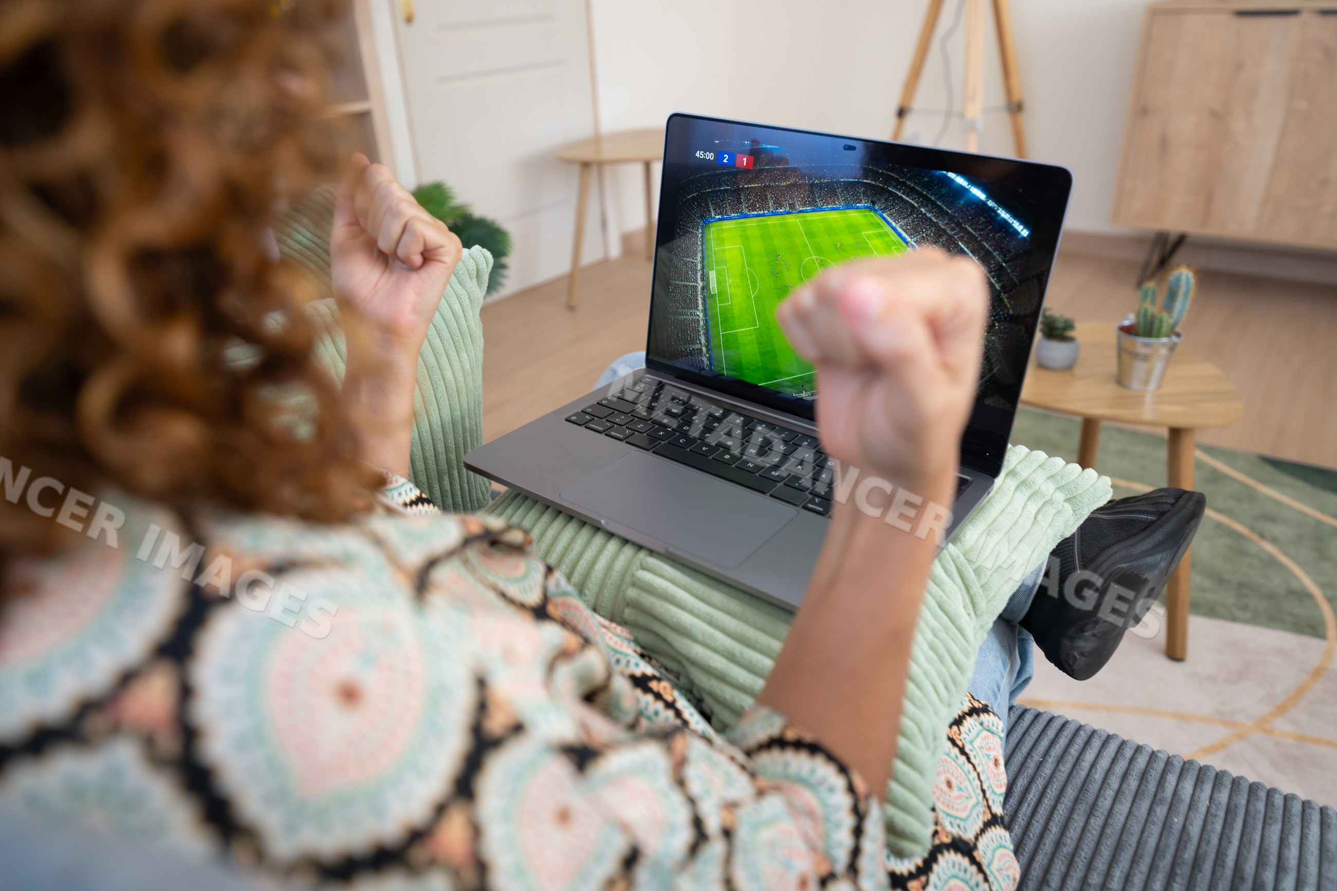 White woman cheering while watching soccer match on laptop