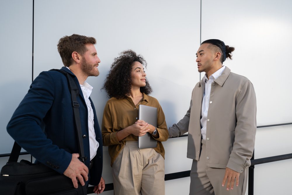 Three young white professionals conversing in an urban outdoor setting