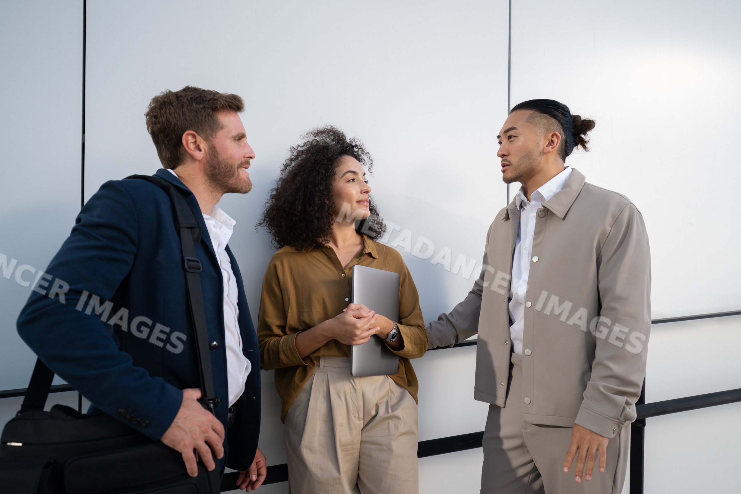 Three young white professionals conversing in an urban outdoor setting