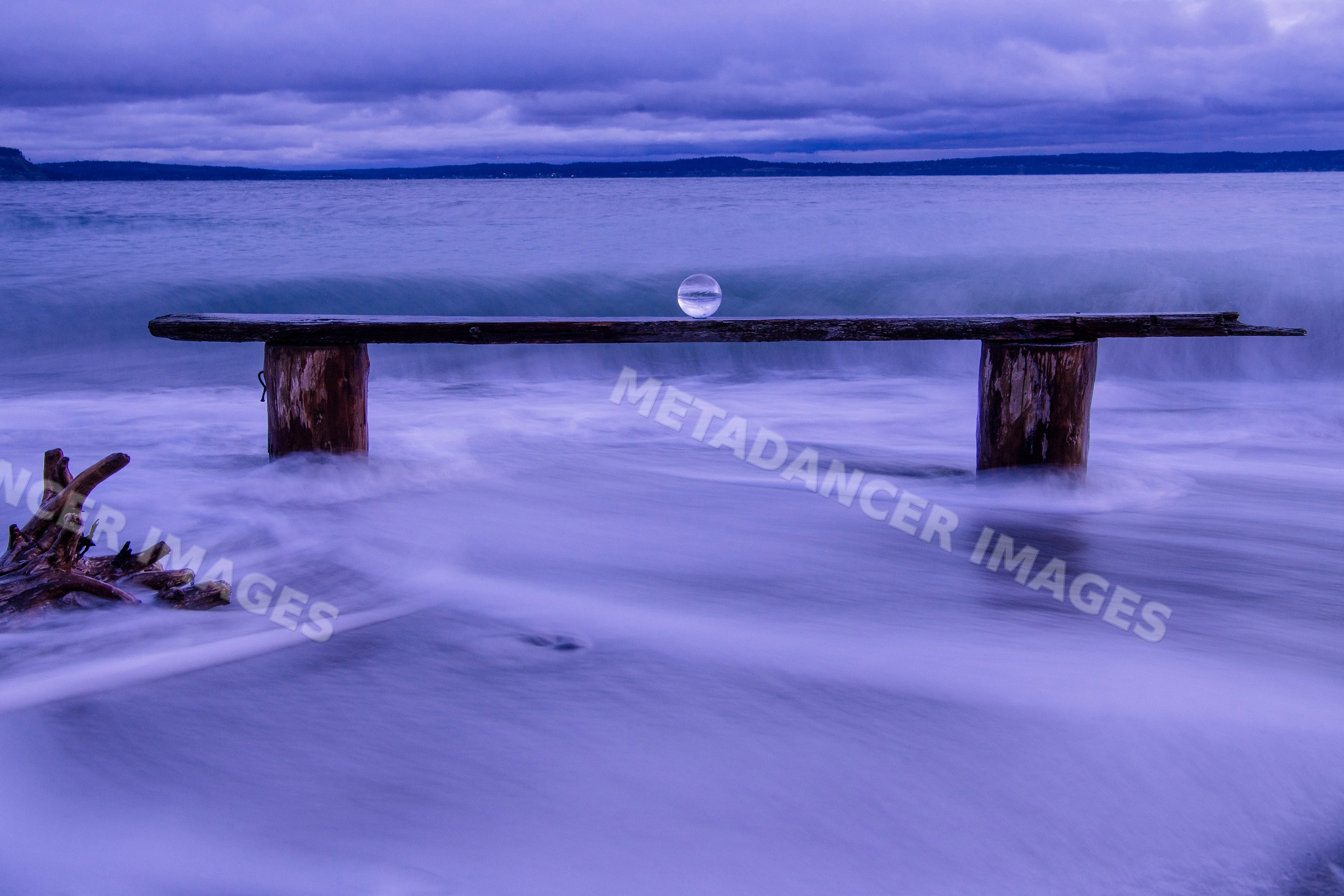 Wooden bench with glass sphere on waves at Norwegian Point beach