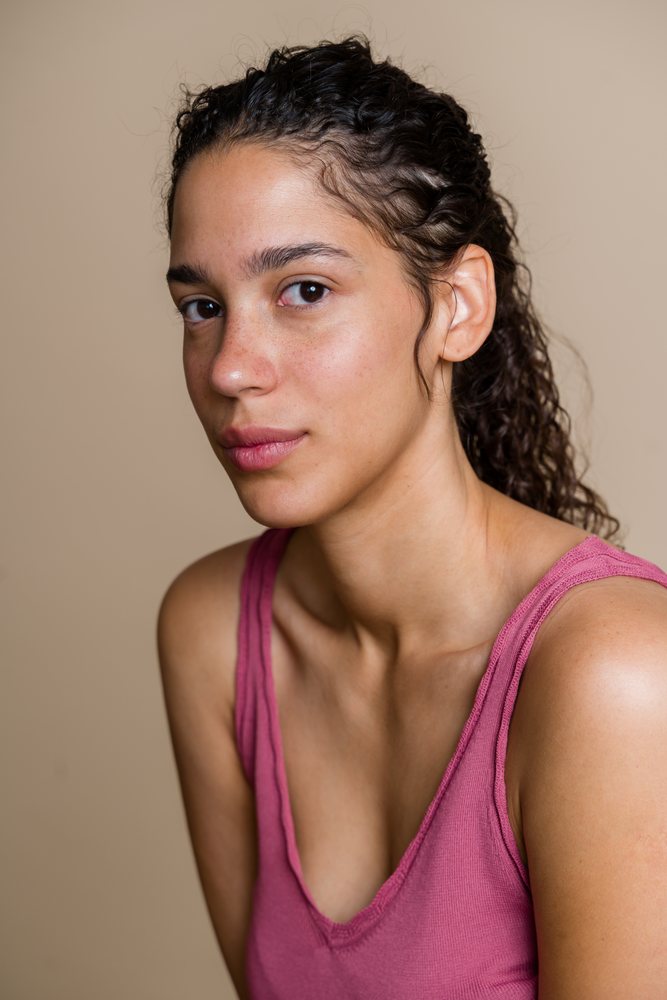 Hispanic woman with curly hair in pink tank top in studio beauty shoot
