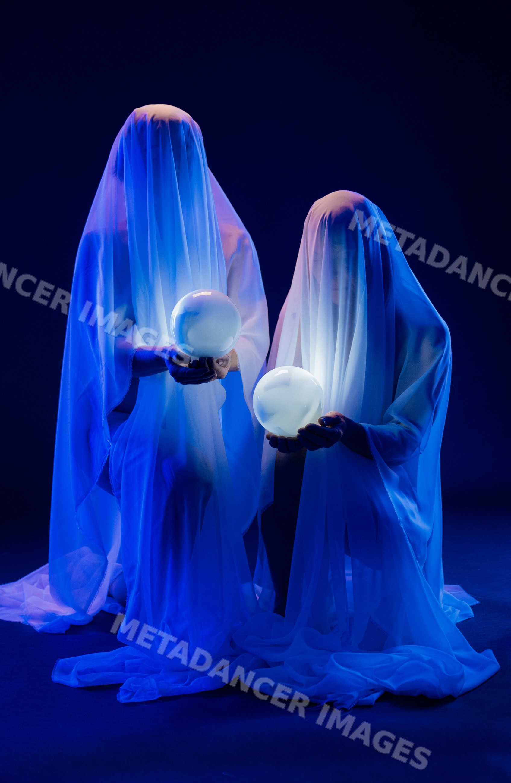 Two ghostly figures holding illuminated crystal balls in blue light