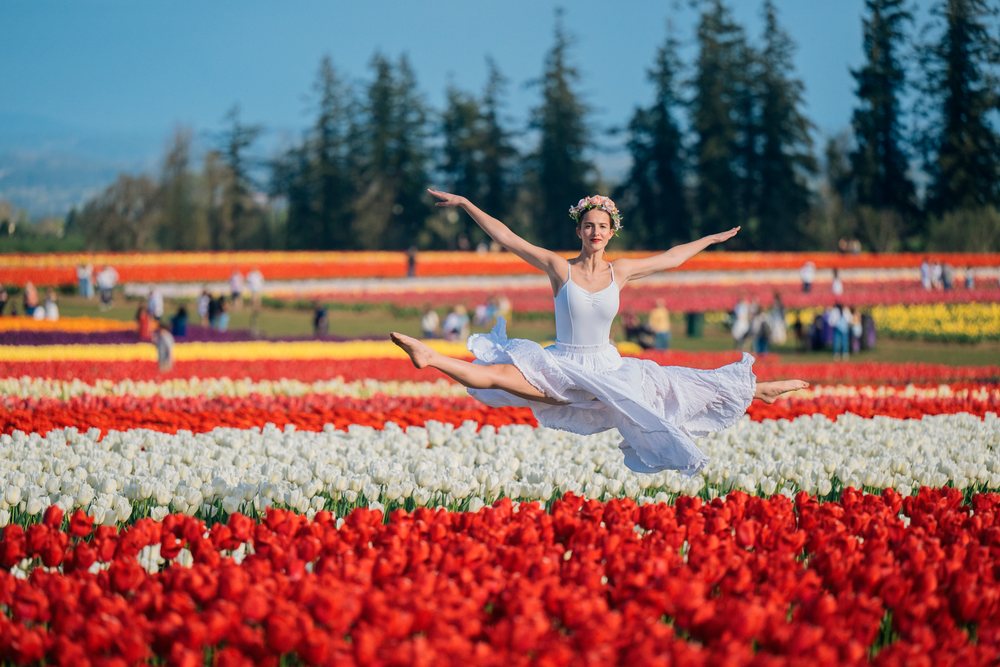 Ballet white dancer leaping in colorful tulip field