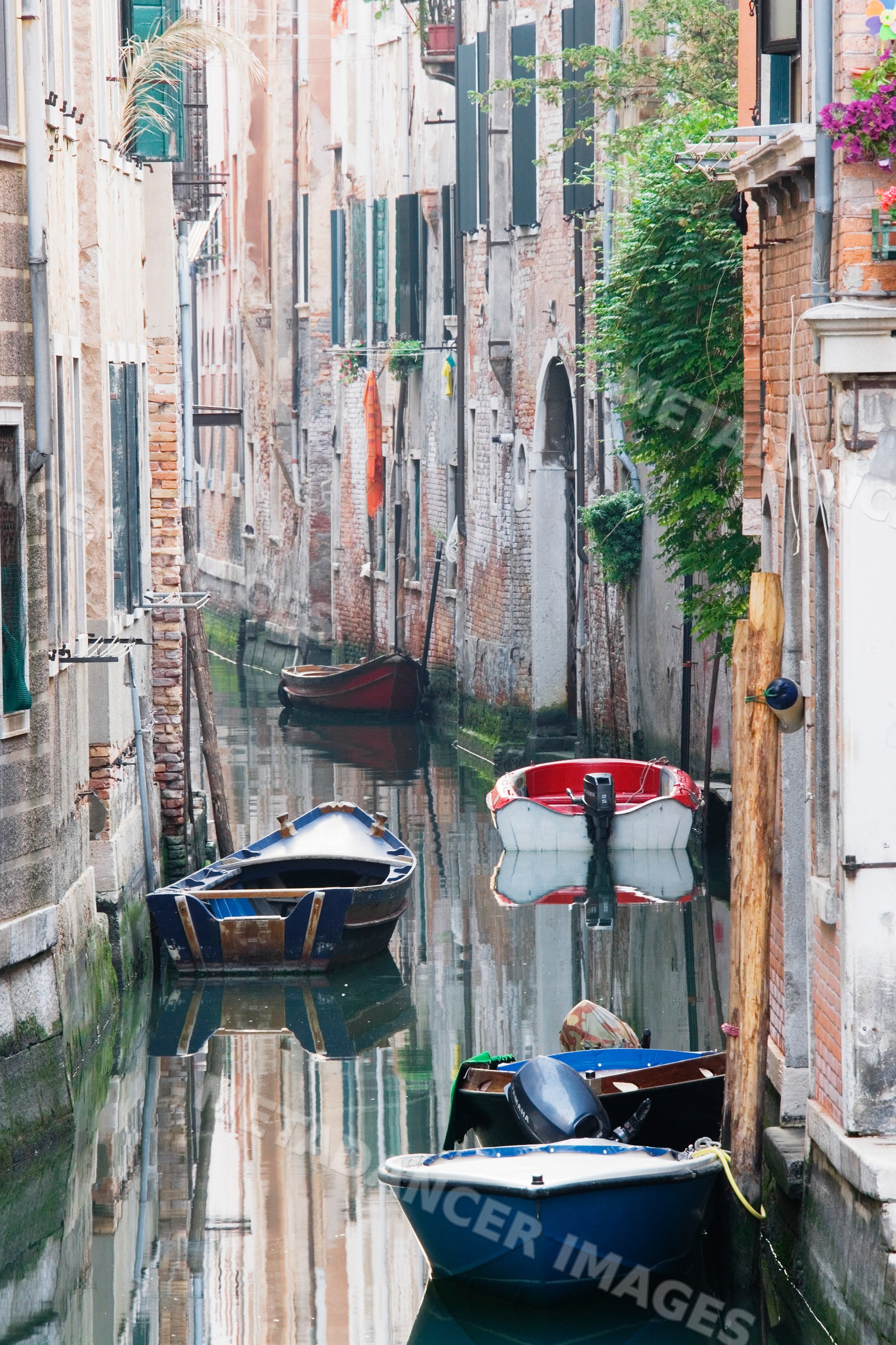 Venice canal with boats along narrow waterway between brick buildings