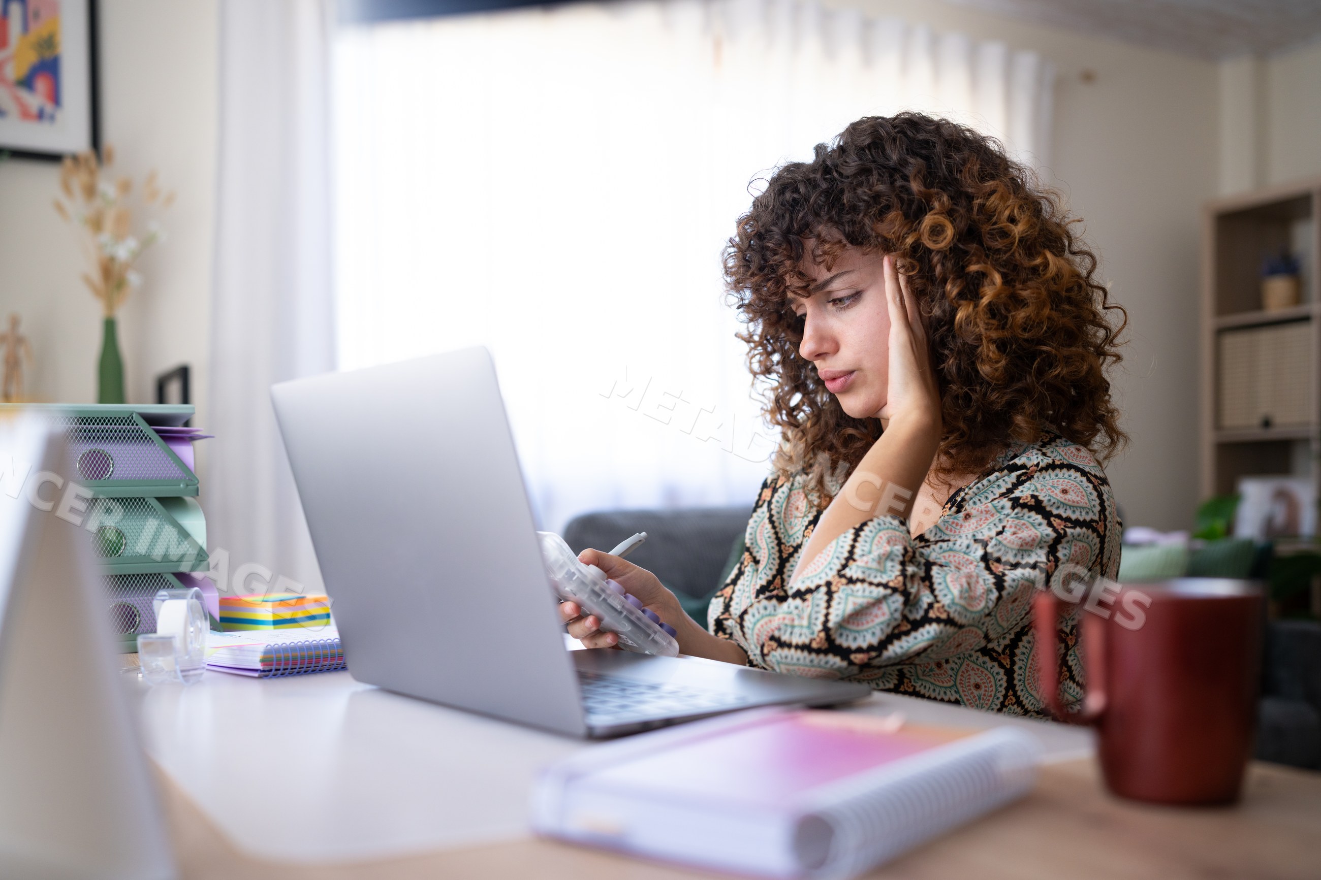 White woman calculating finances at a home office desk in a office