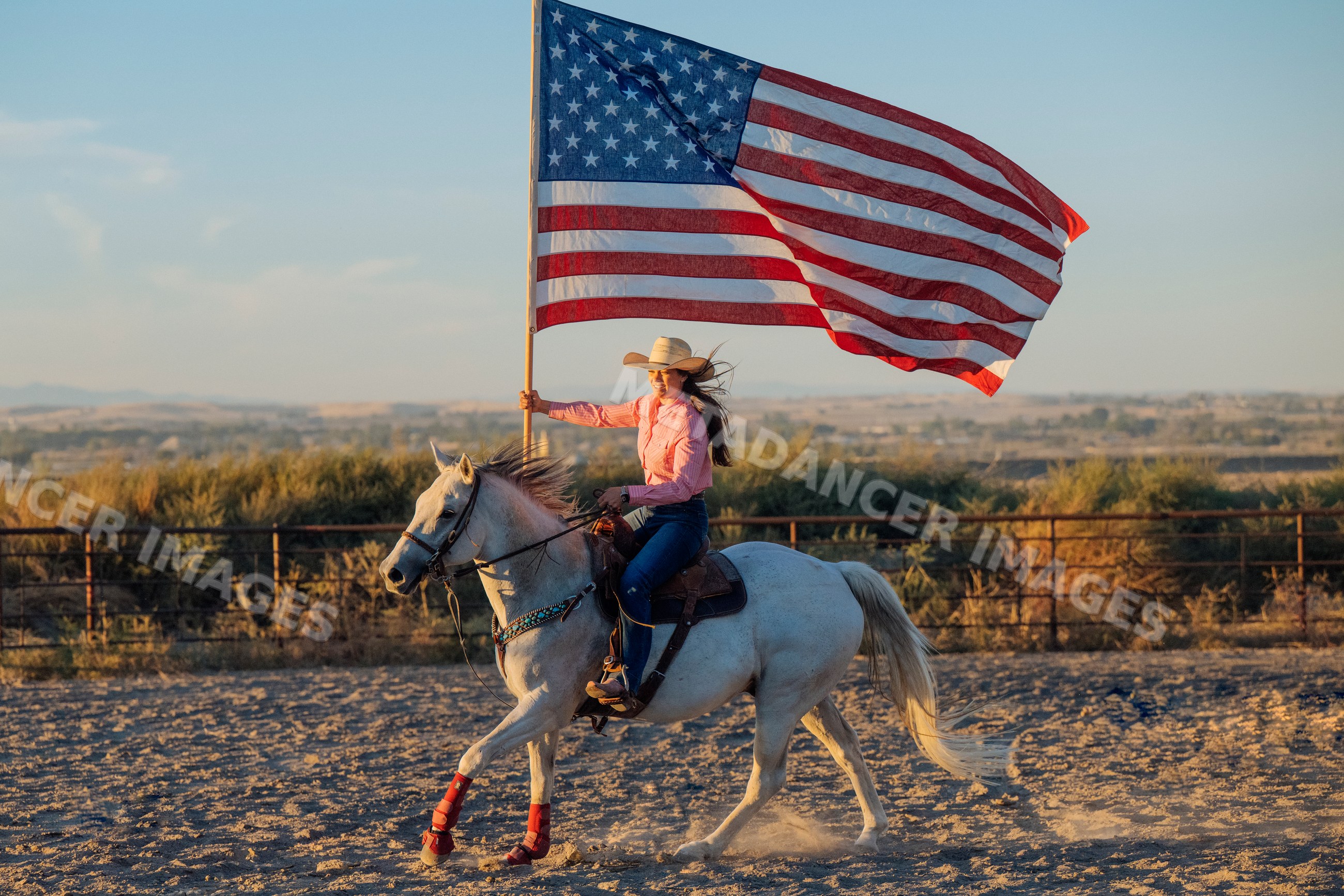 White woman riding horse with american flag in Southwest USA desert